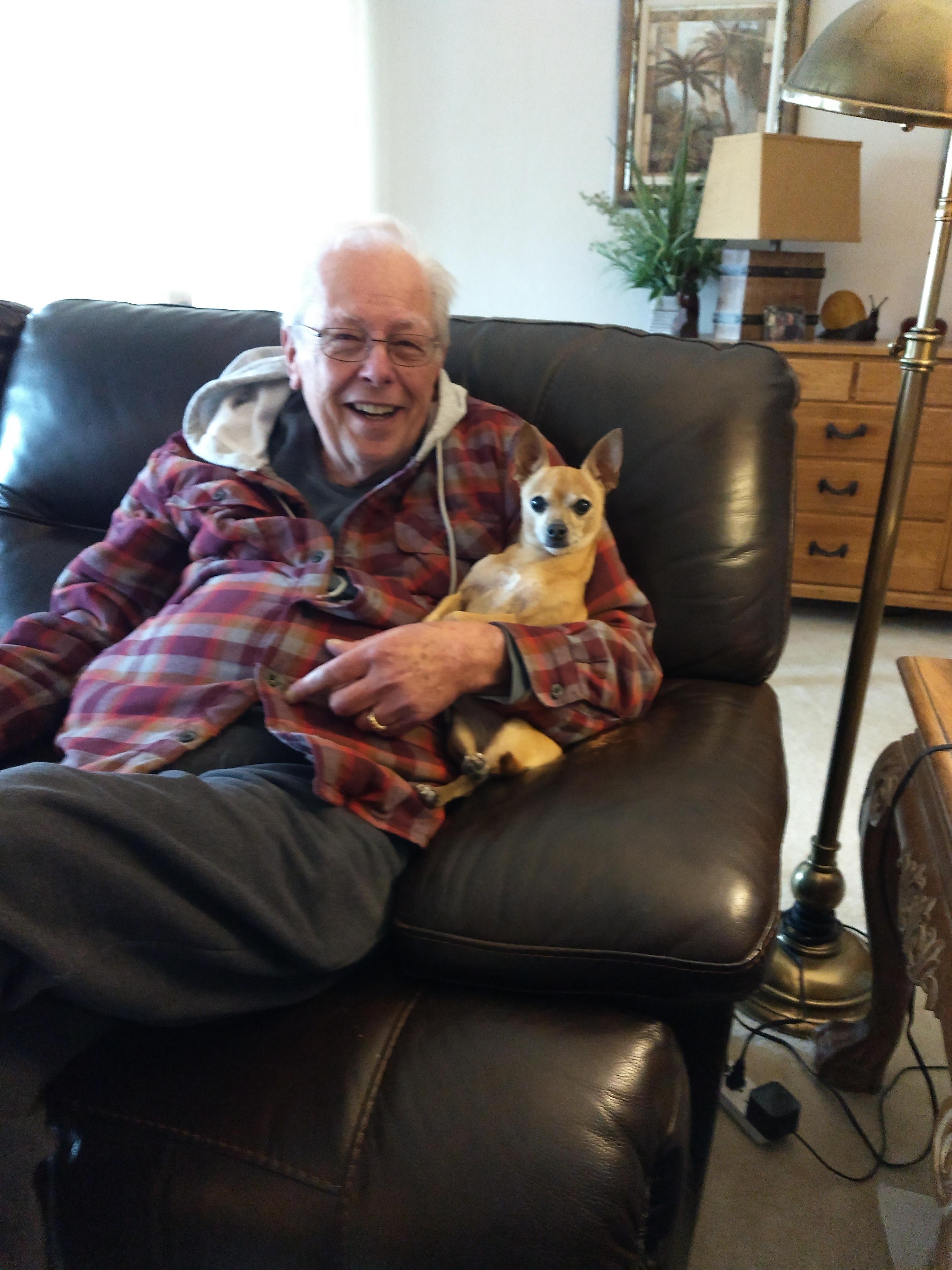 A man sitting on a couch with a dog