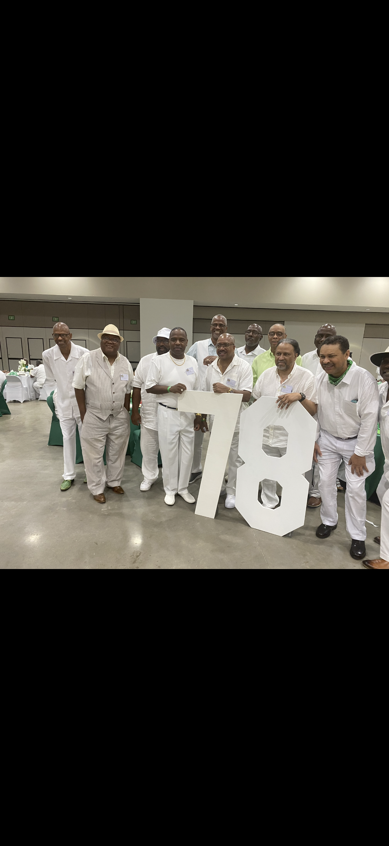 A group of men in white outfits holding a large white sign