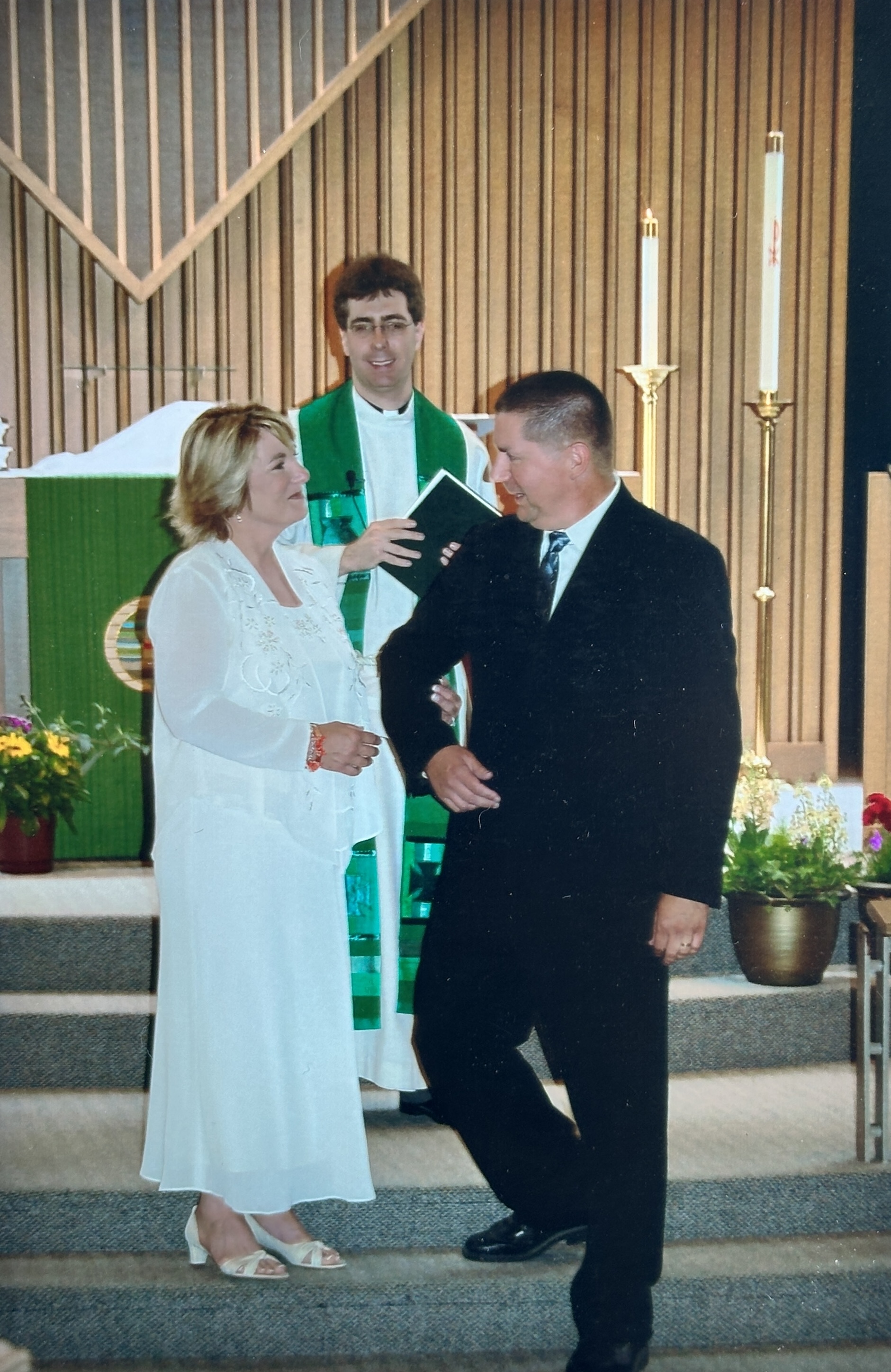 A man and woman standing in front of a man in a robe
