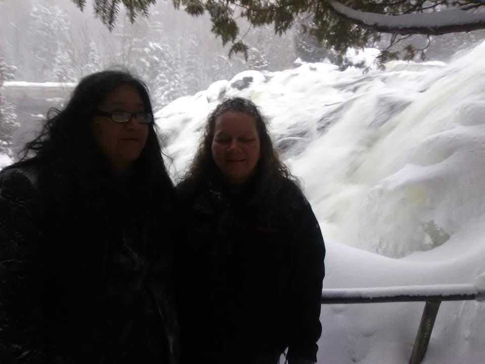 Two women standing in front of a waterfall