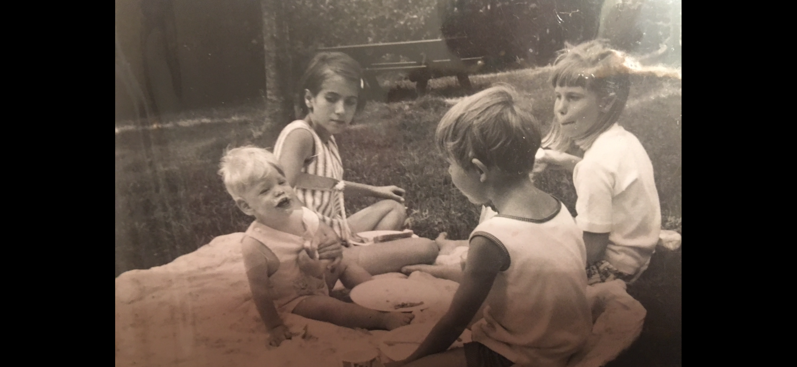 A group of children sitting on a blanket in a yard