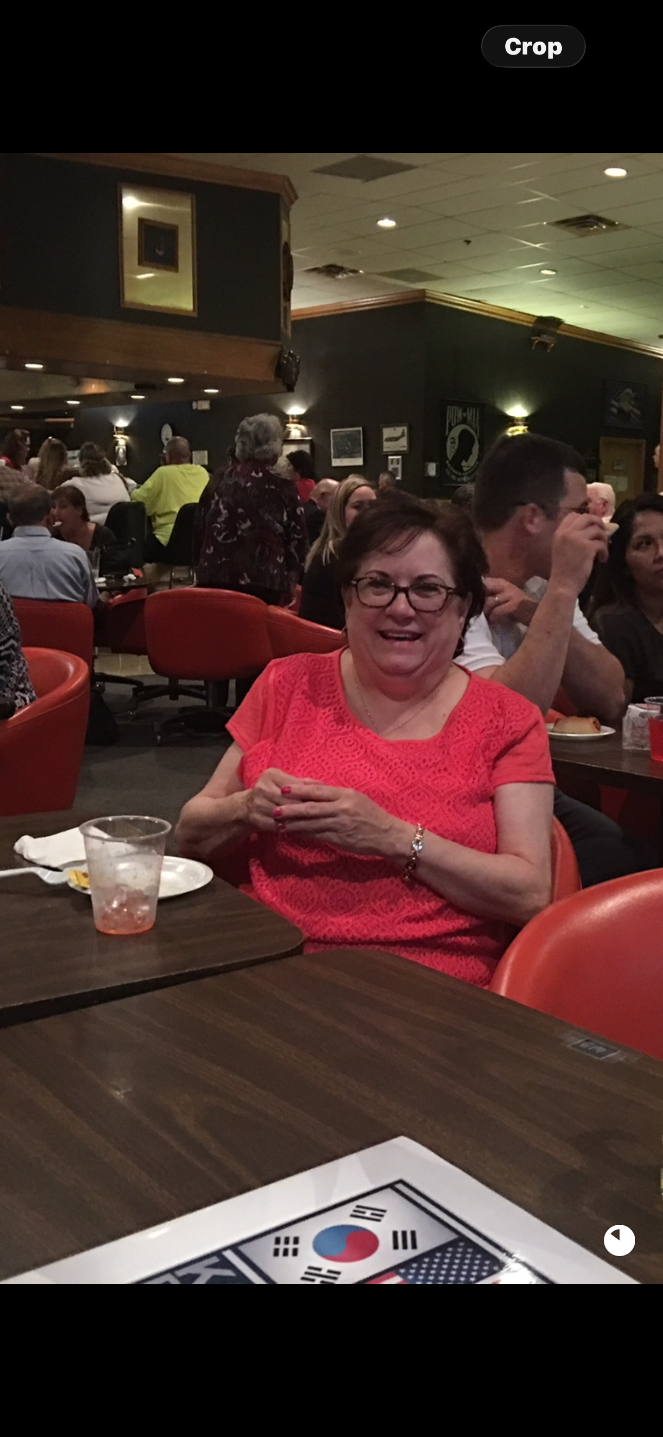 A woman sitting at a table with a group of people in the background