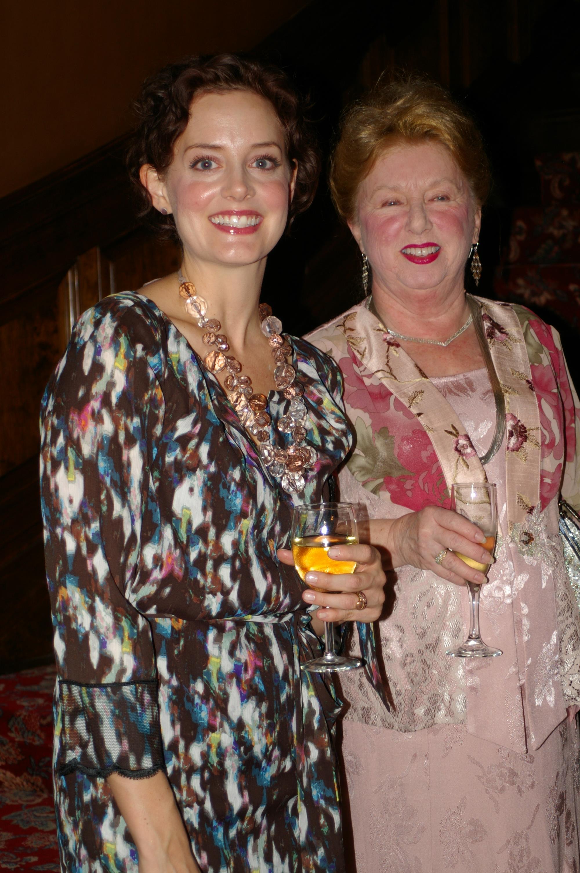 A woman holding wine glasses and smiling at camera