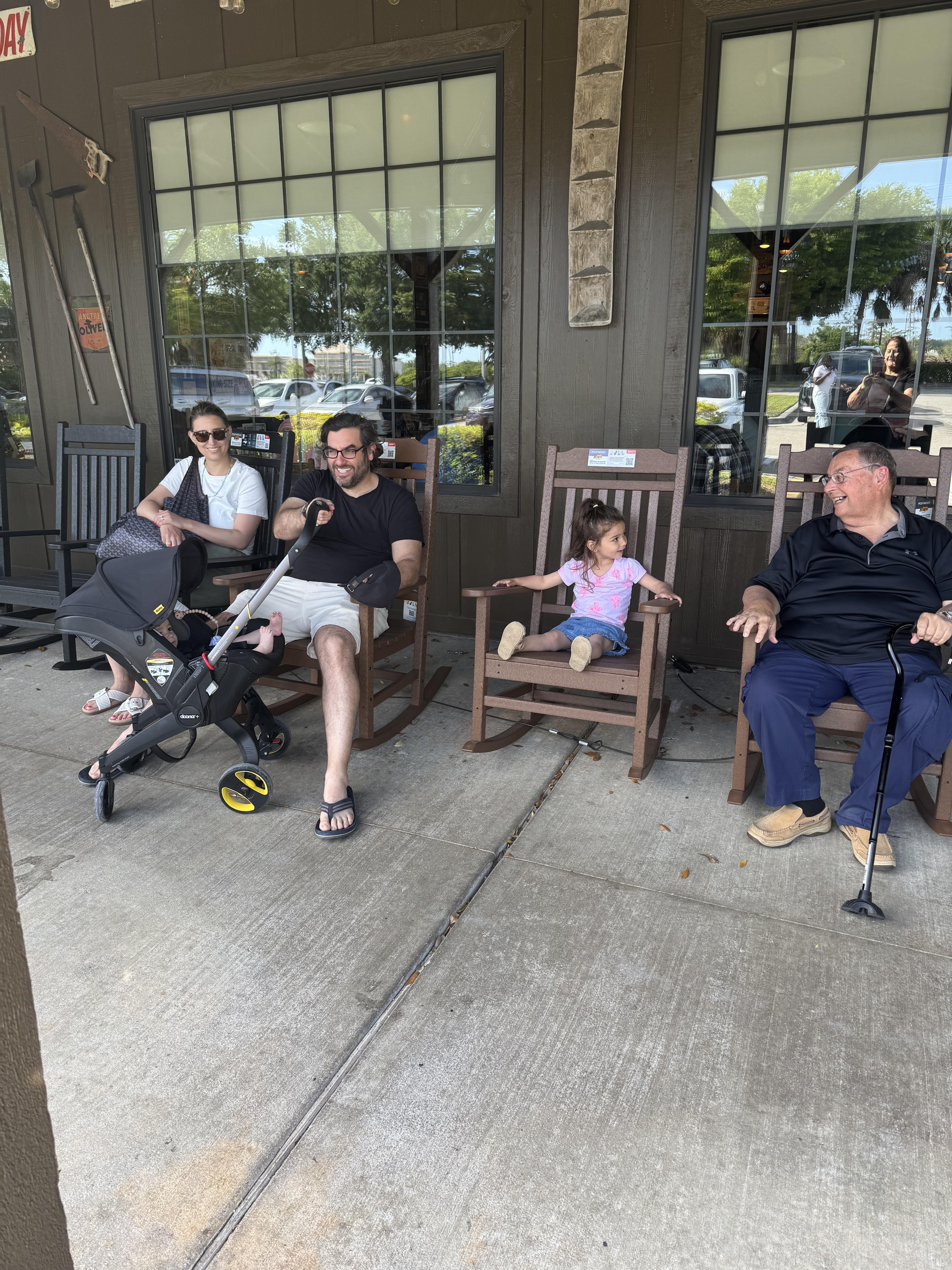 A group of people sitting in rocking chairs outside a building