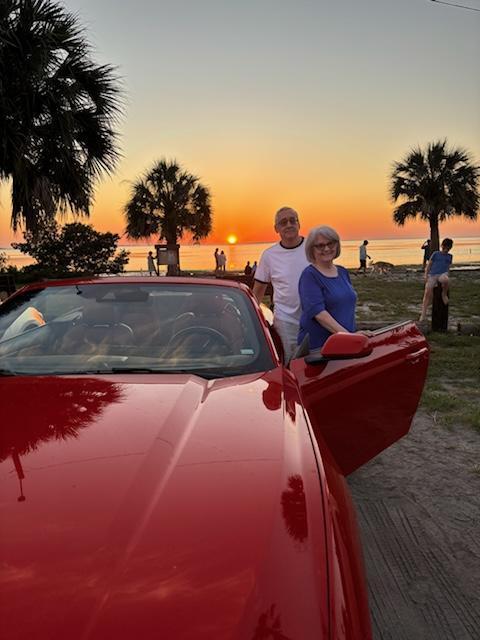 A man and woman standing next to a red car