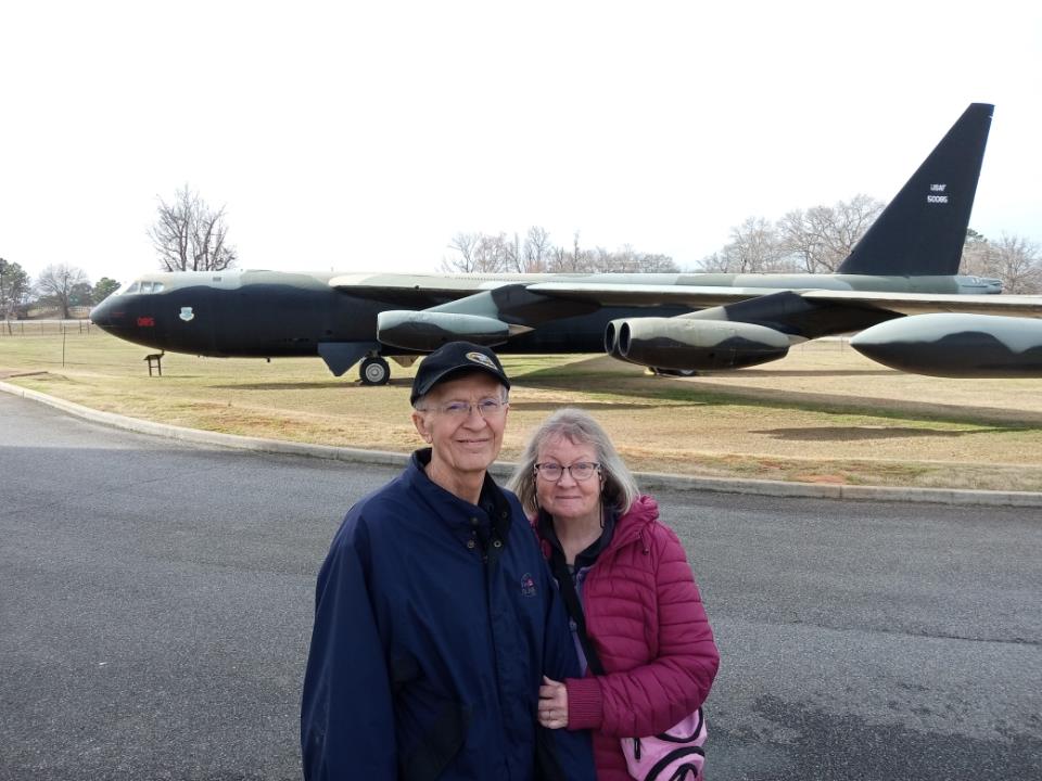 A man and woman standing in front of a large airplane