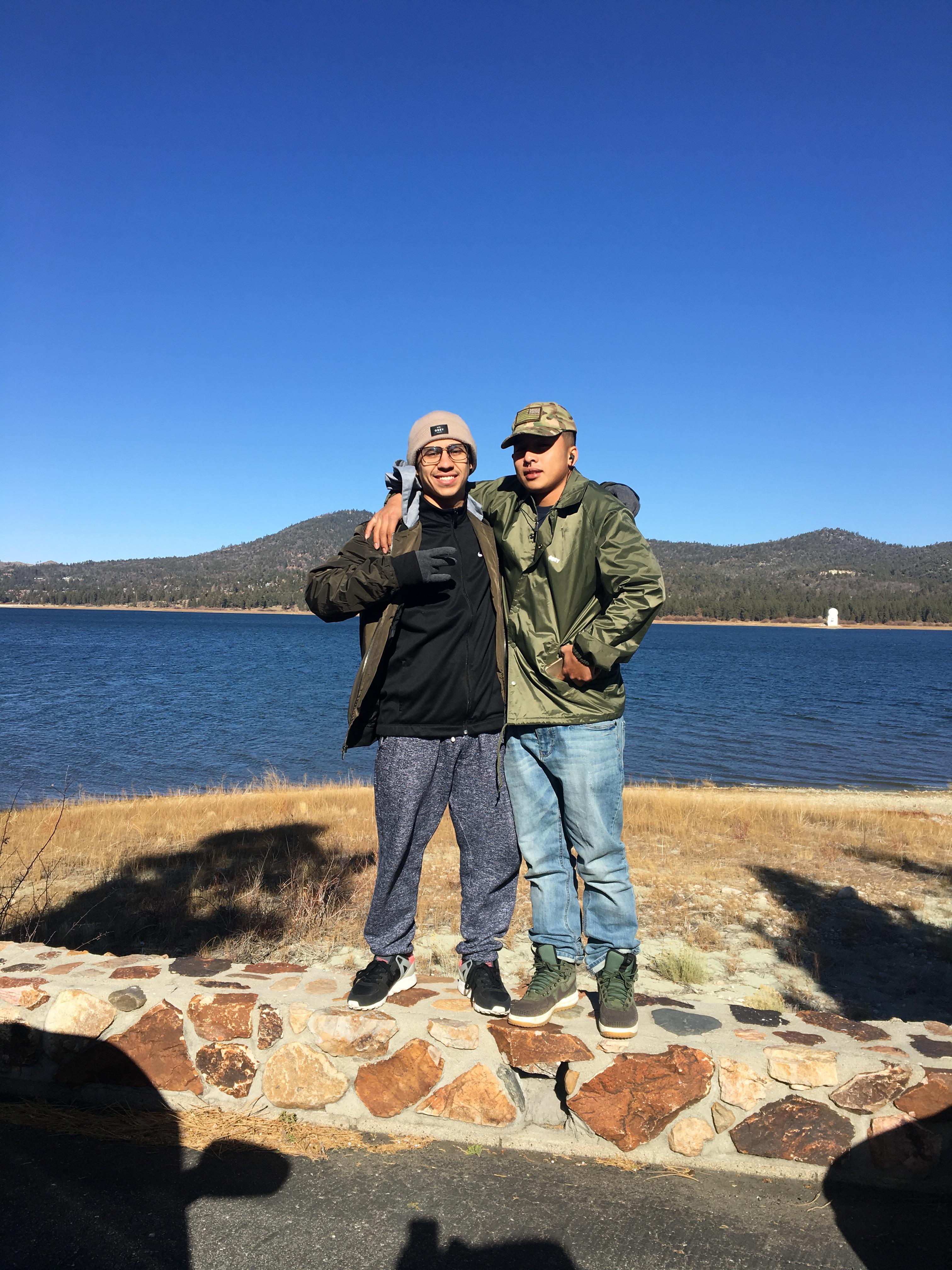 Two men standing on a rock wall next to a body of water