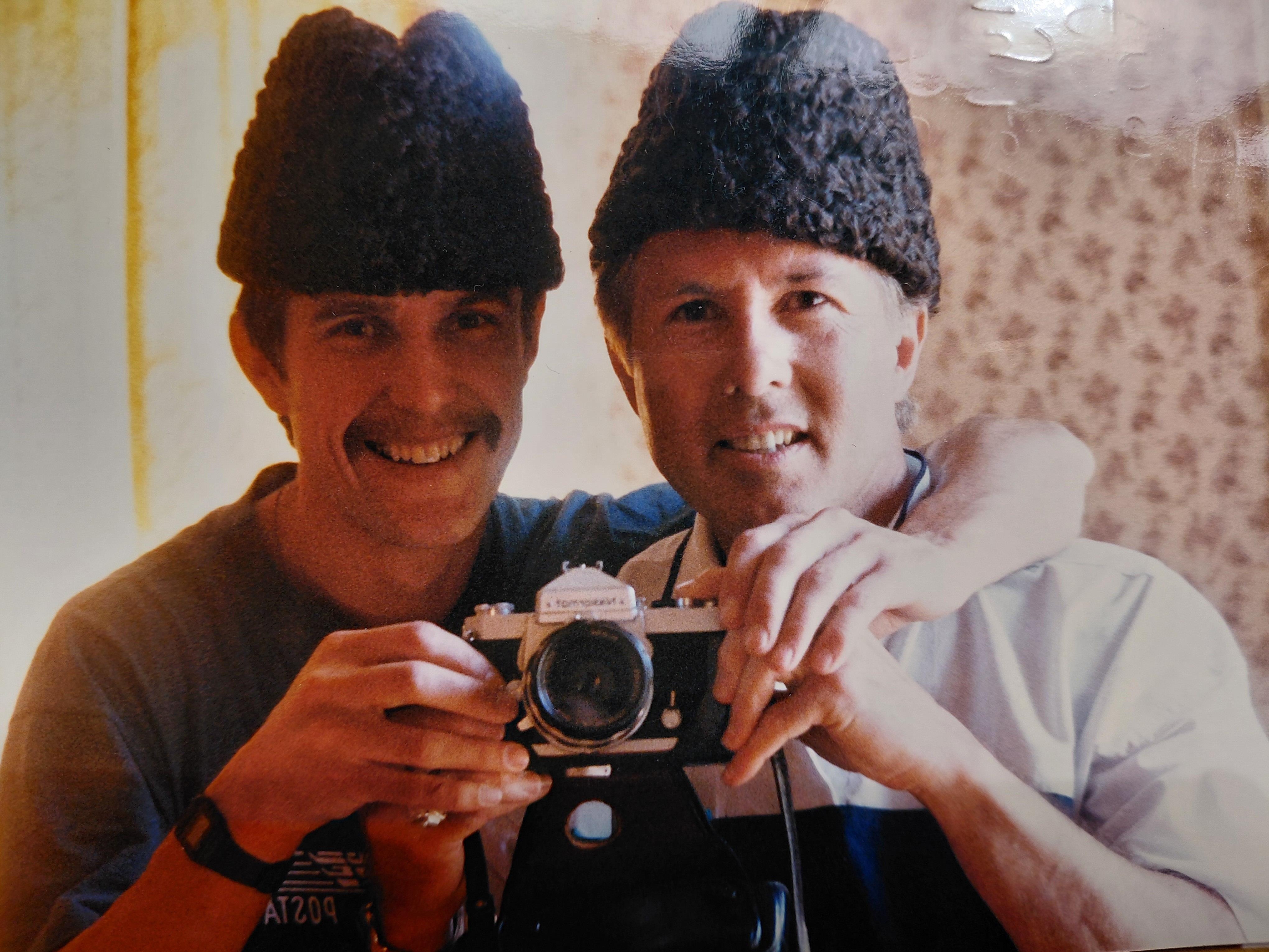 Two men wearing hats and holding a camera