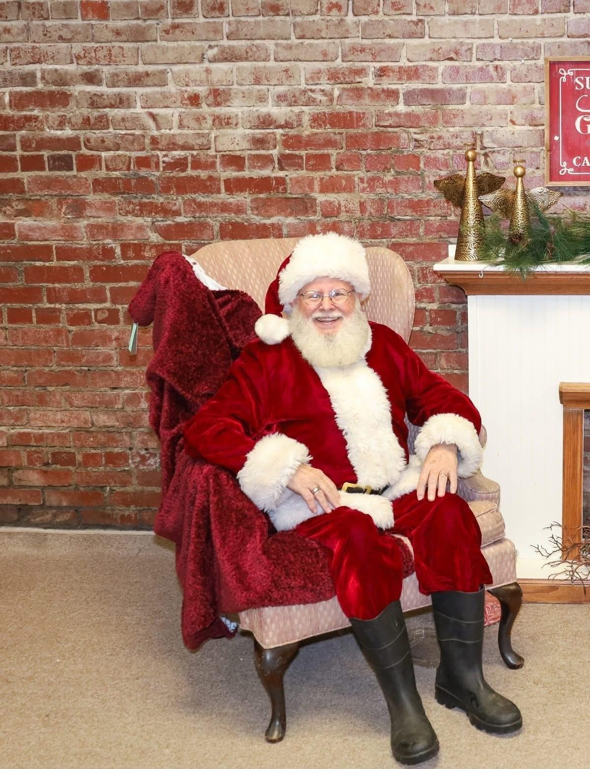 A man in a santa claus garment sitting in a chair