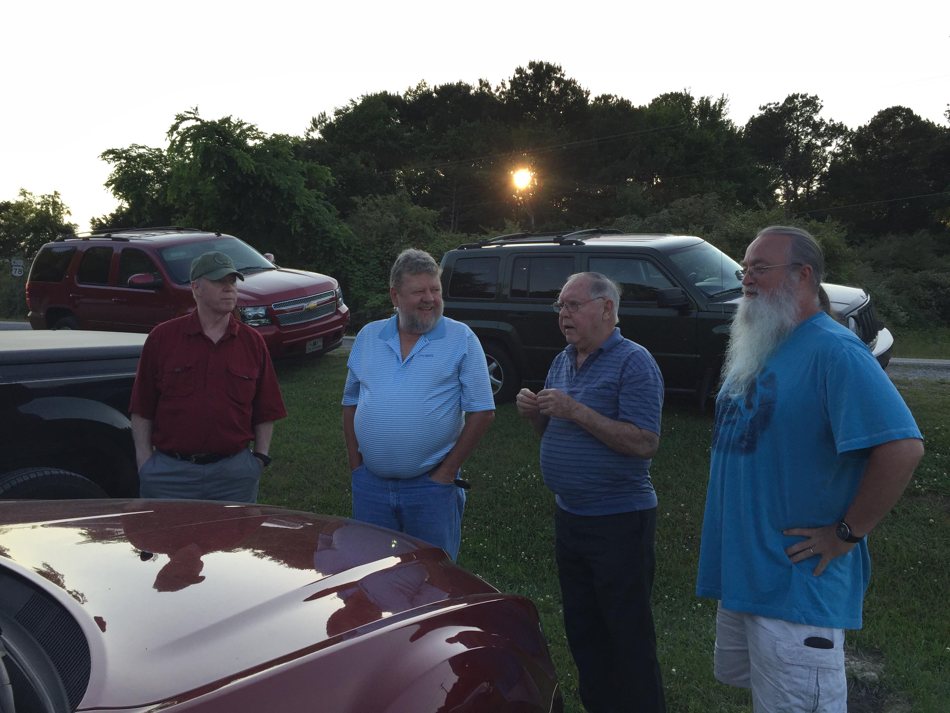 A group of men standing next to a car