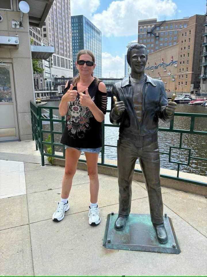 A woman standing next to a statue of a man