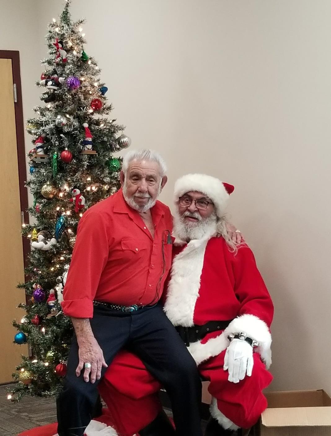 Two men in santa clothing posing for a picture