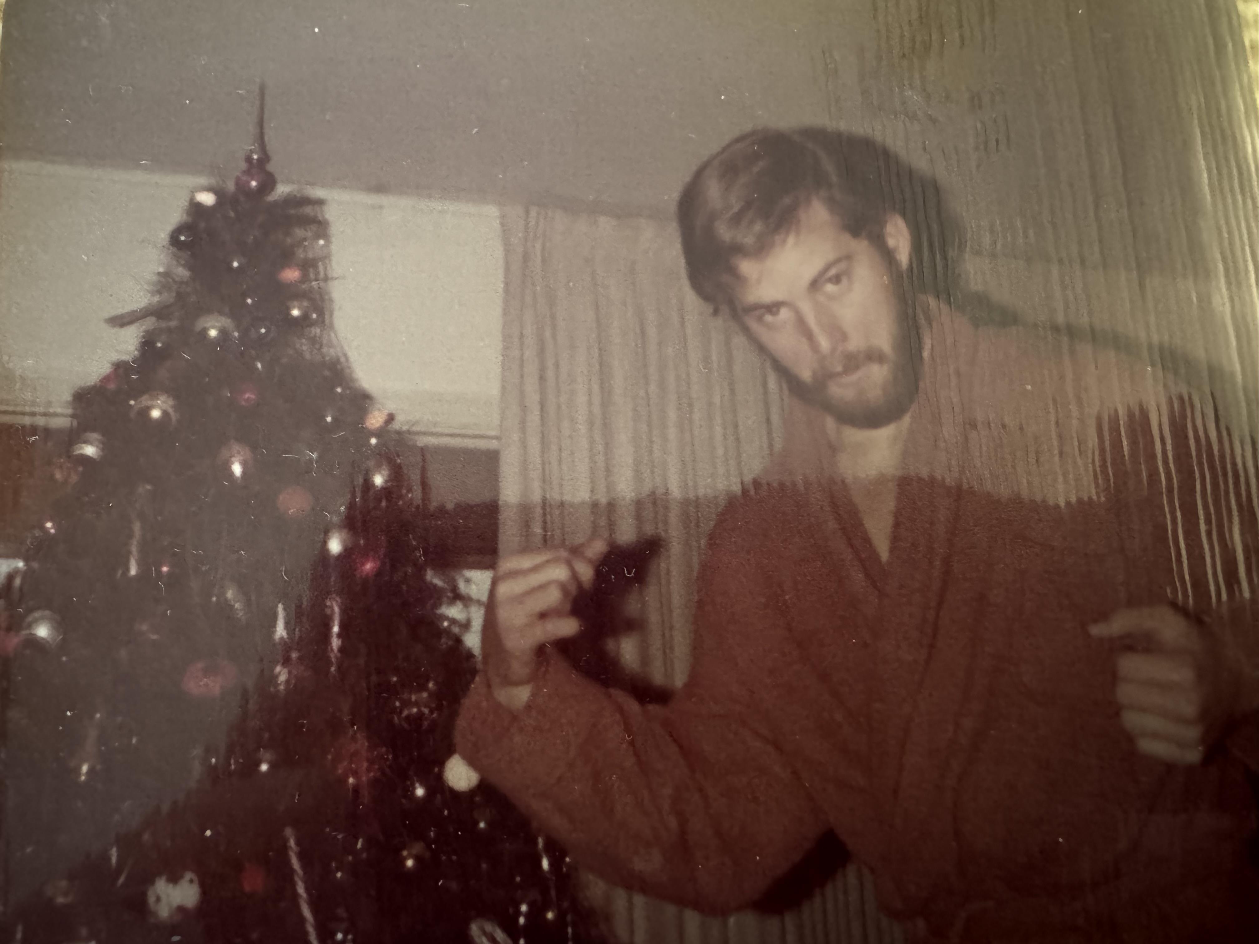 A man in a robe standing next to a christmas tree