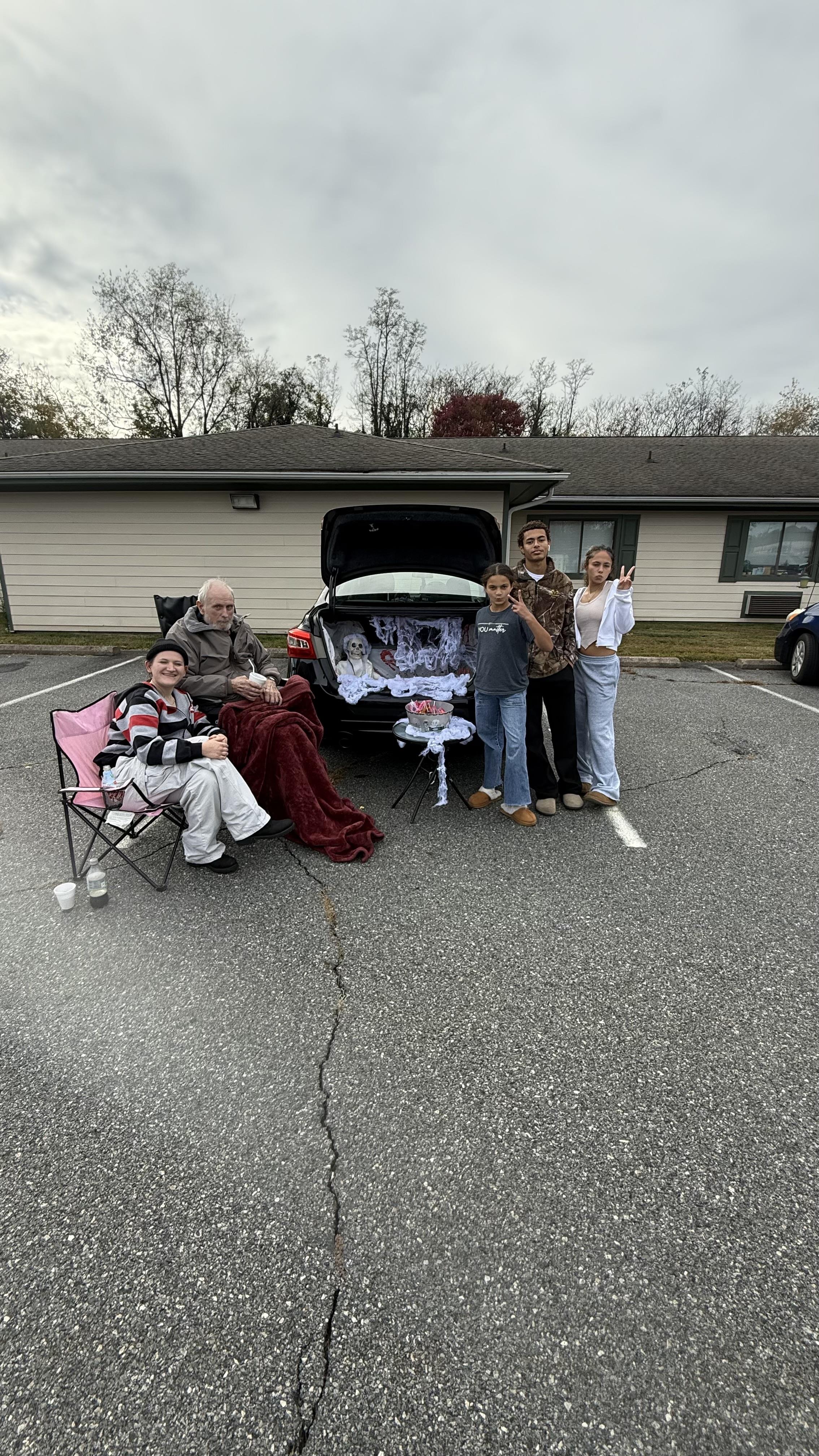 A group of people standing in front of a car