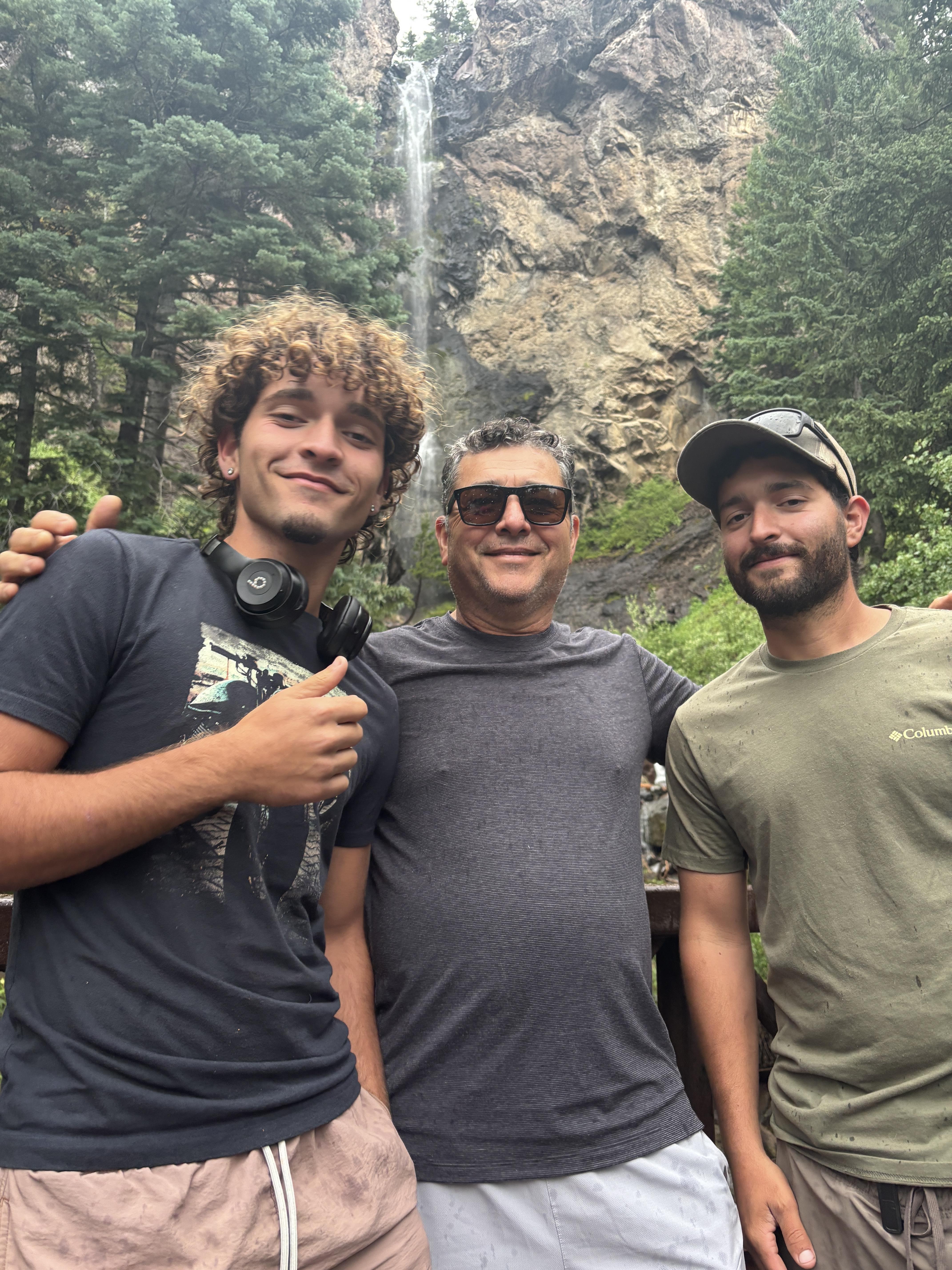 A group of men standing in front of a waterfall