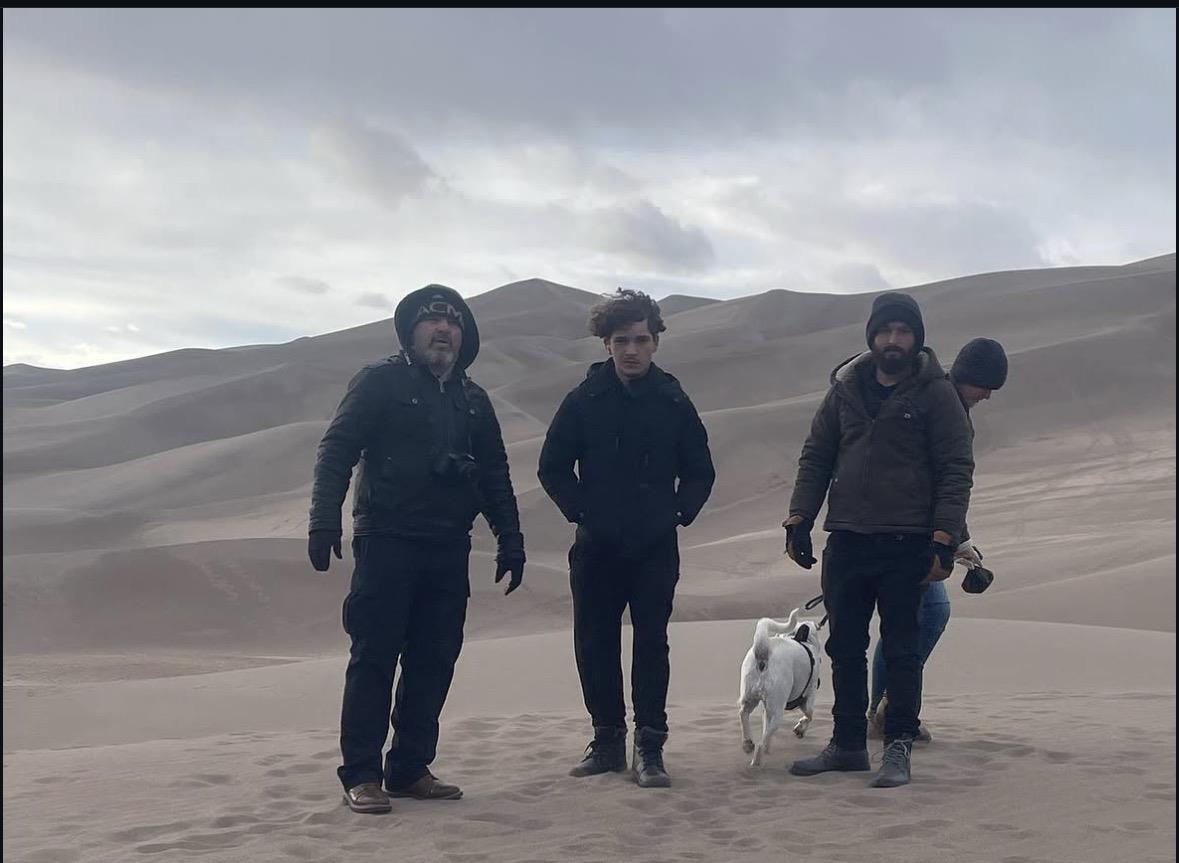 A group of people walking a dog in the desert
