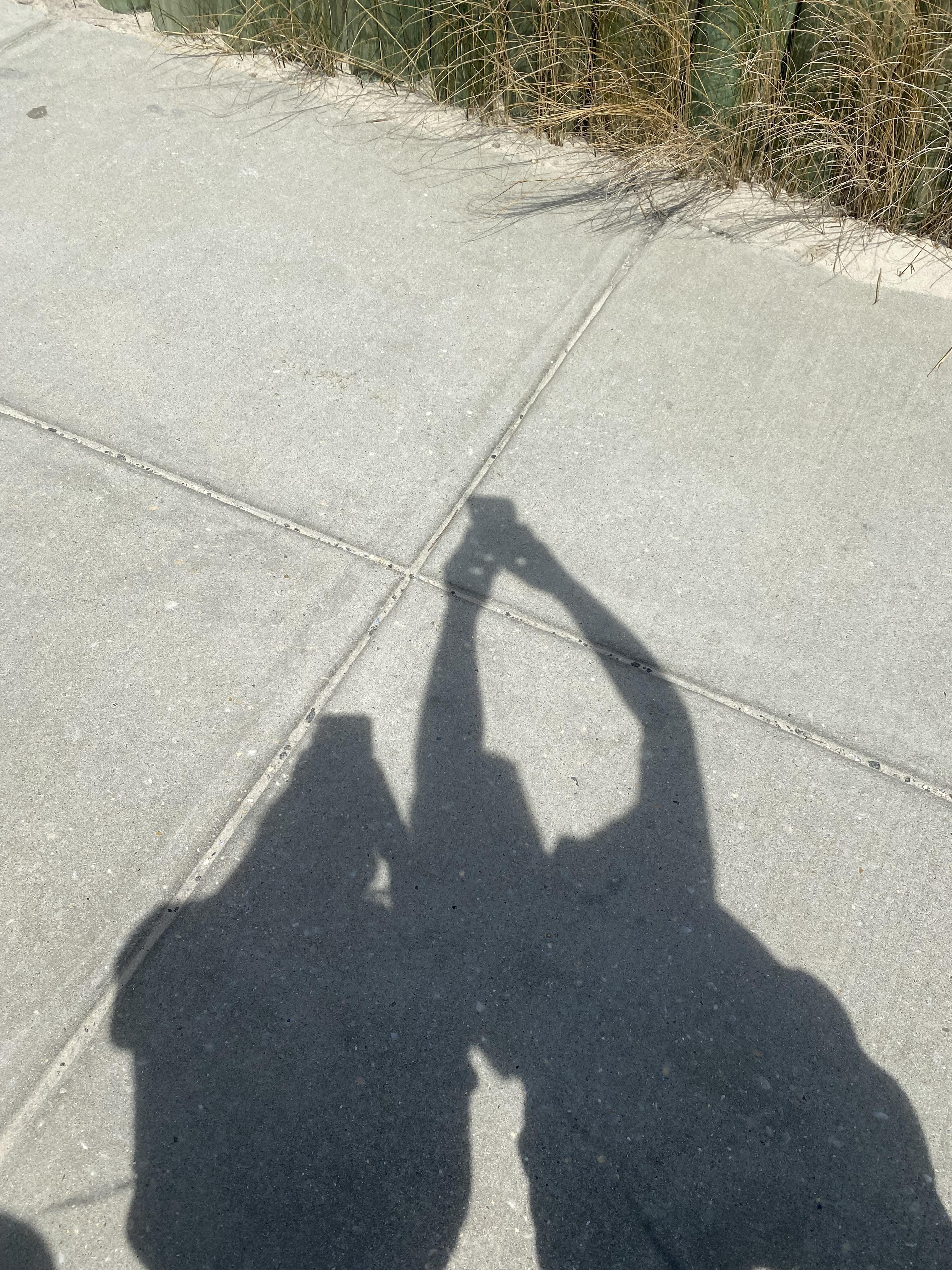 Shadows of people holding hands on a sidewalk