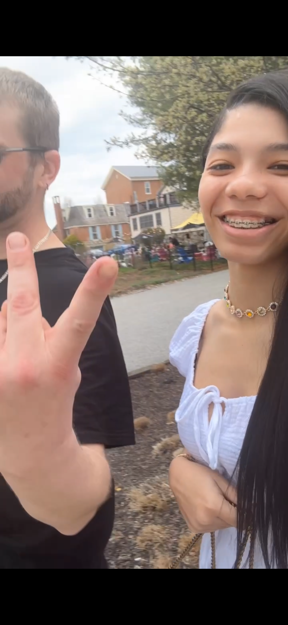 A woman with braces and a man with a peace sign