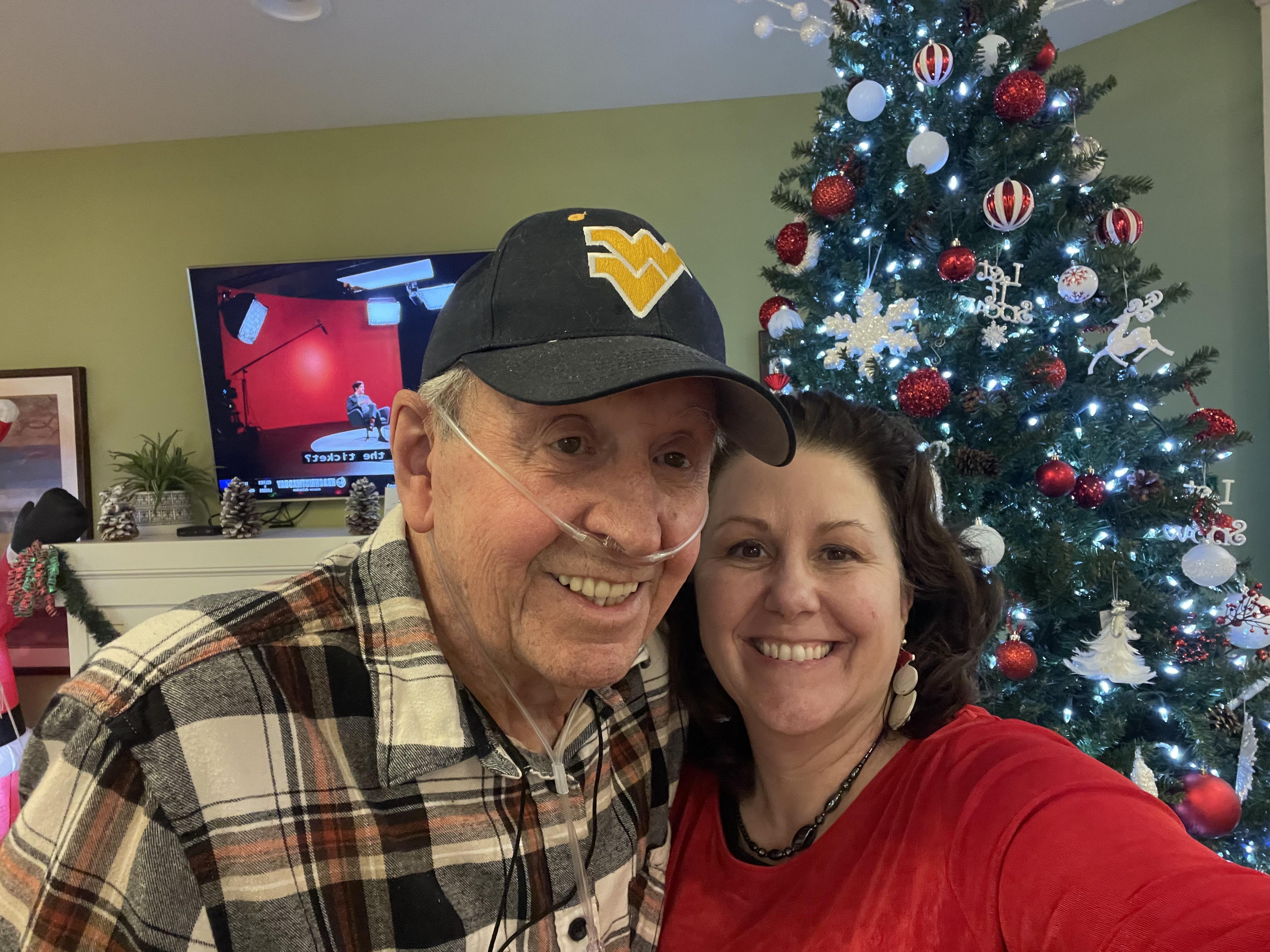 A man and woman taking a selfie in front of a christmas tree