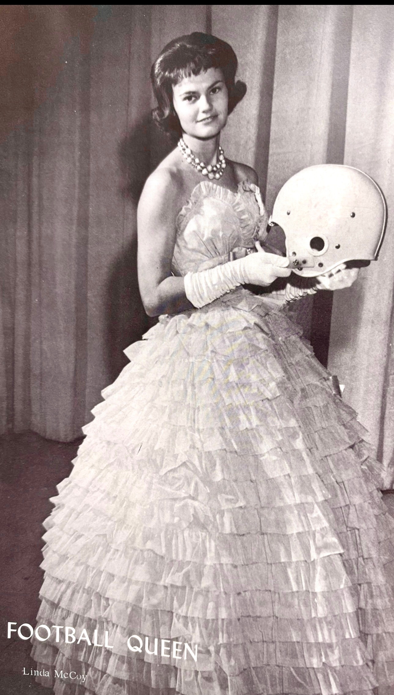 A woman in a dress holding a football helmet