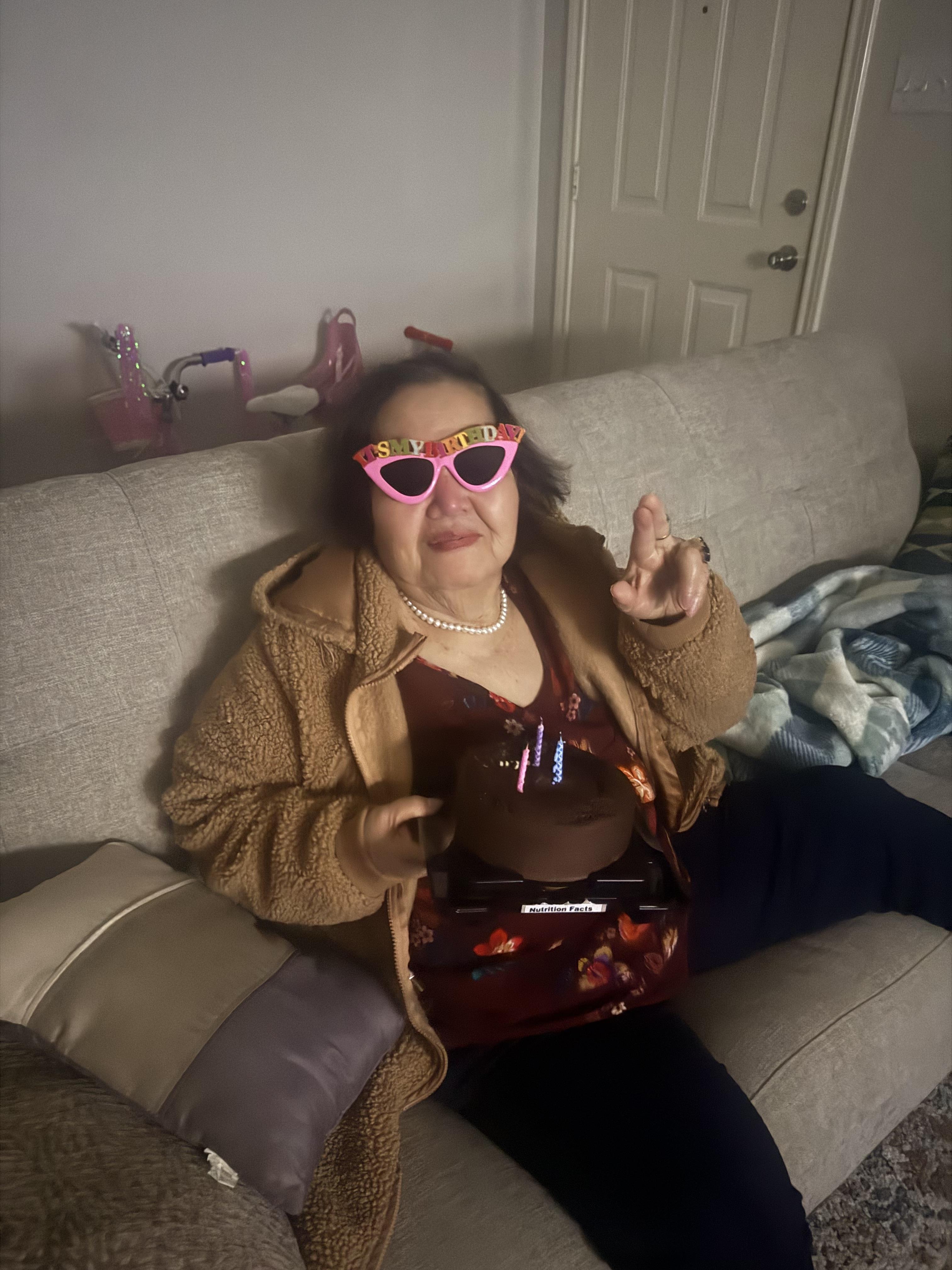 A woman sitting on a couch holding a cake