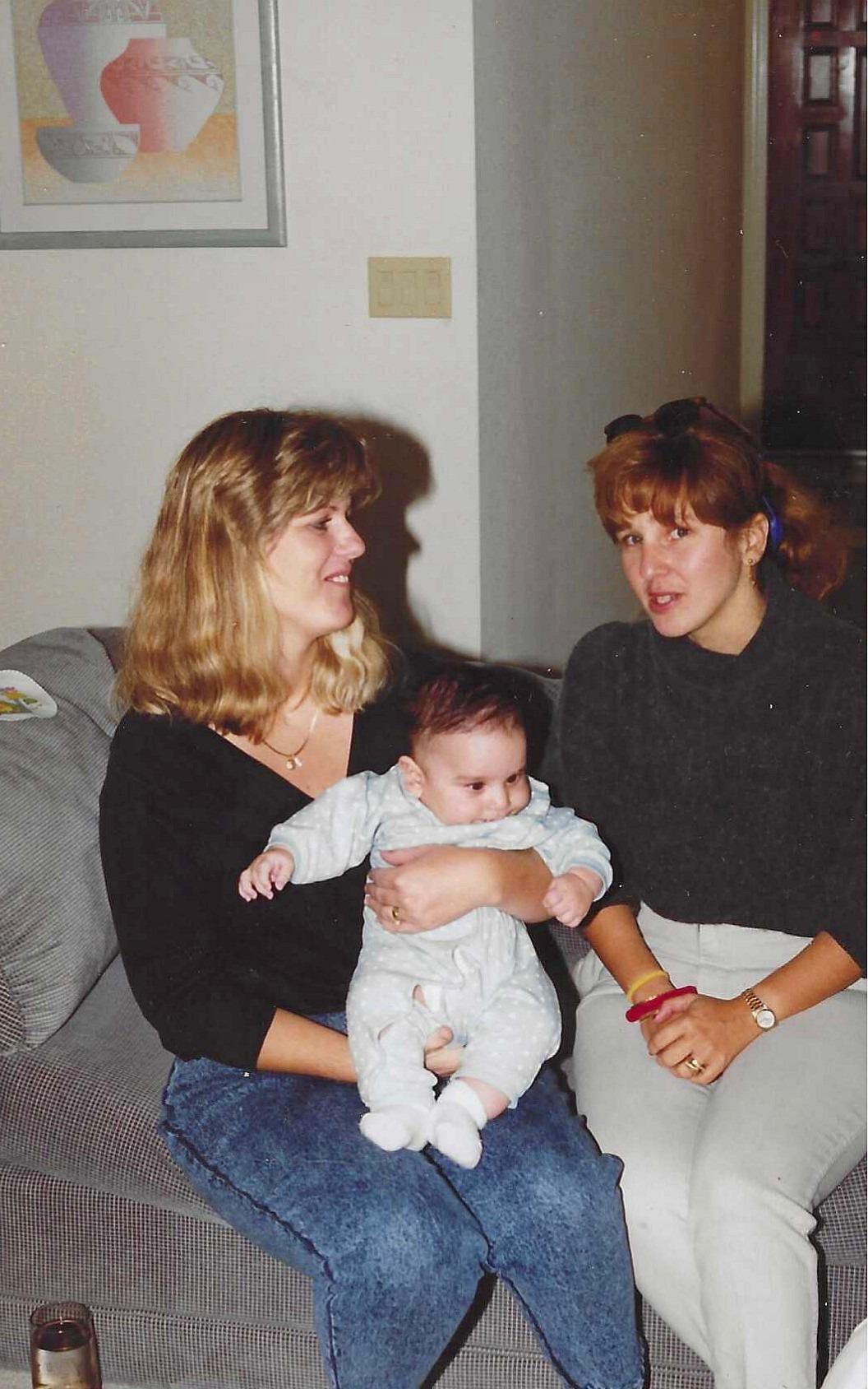 A group of women sitting on a couch holding a baby