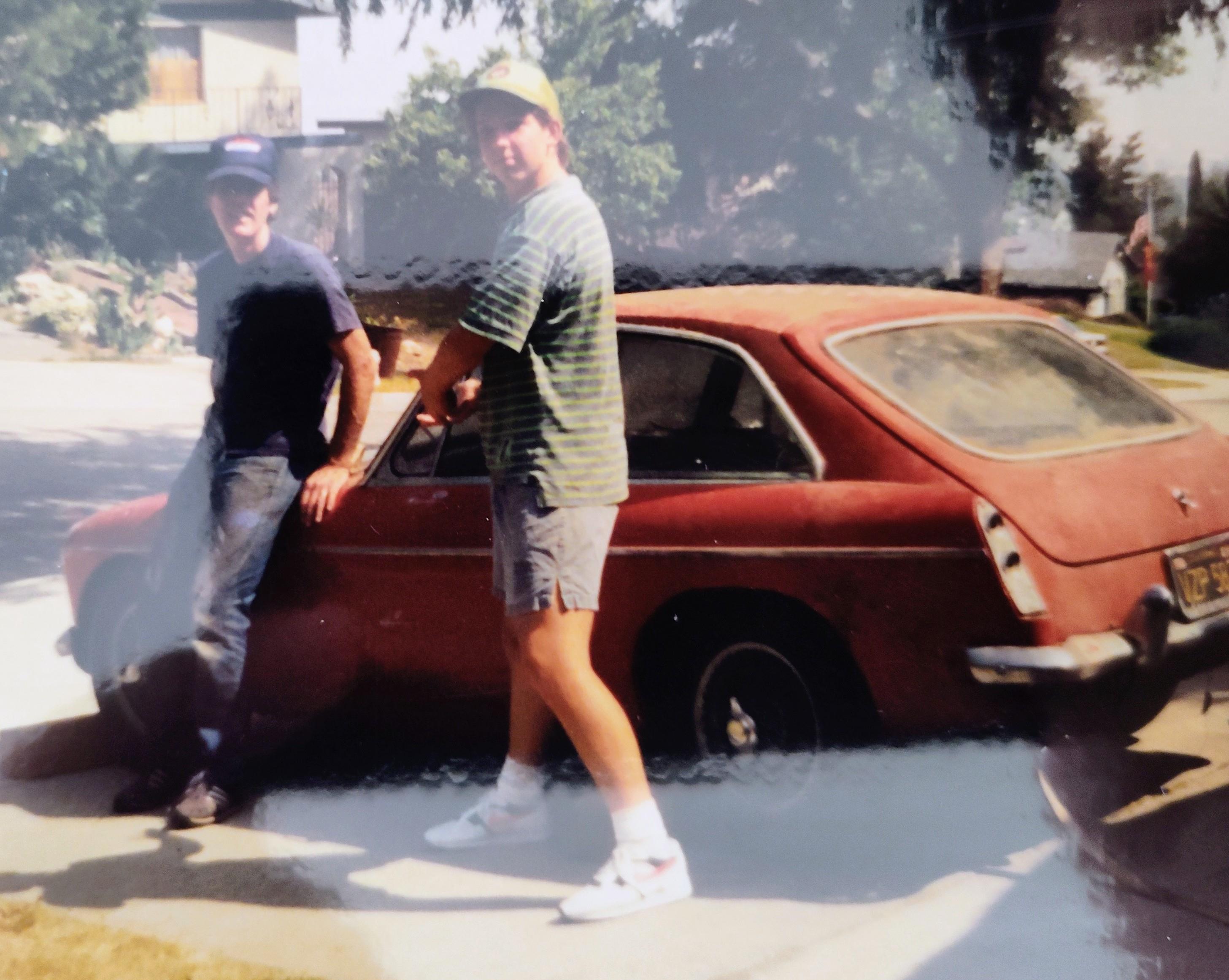 Two men standing next to a car