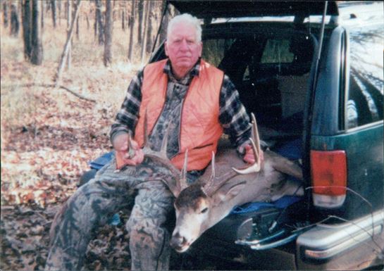 A man holding a deer in the back of a car