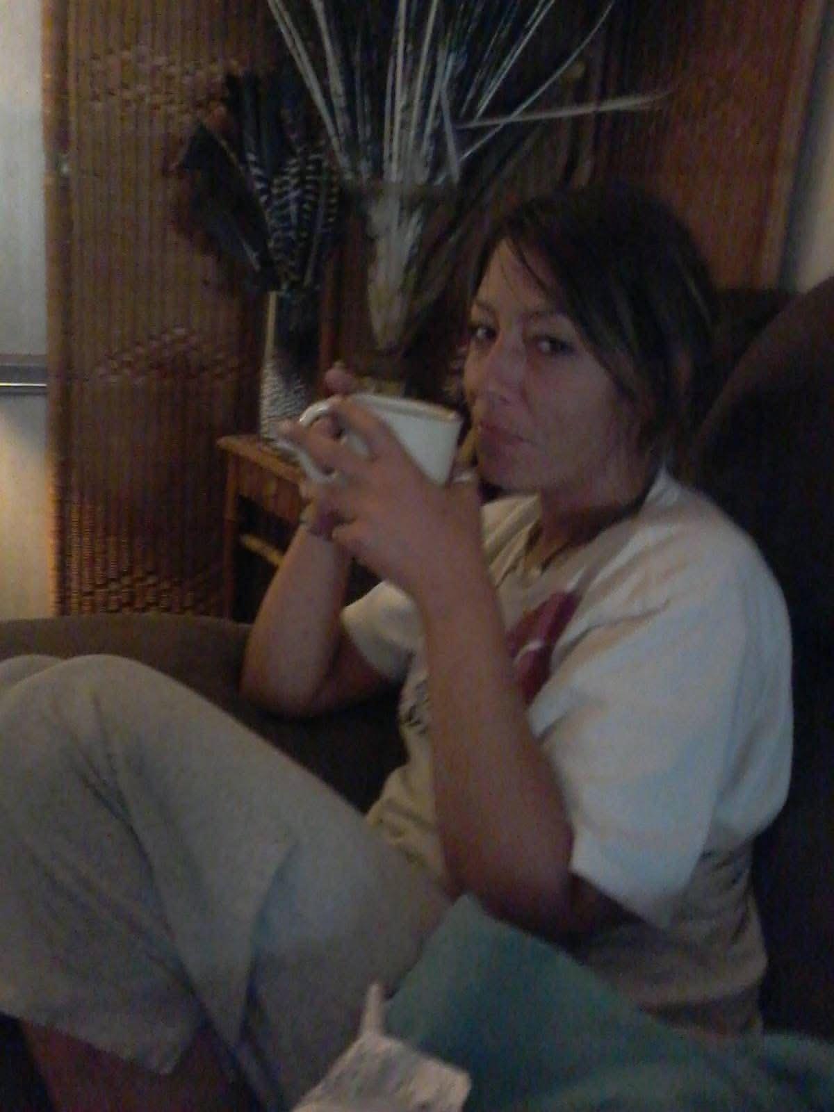 A woman sitting on a couch holding a cup