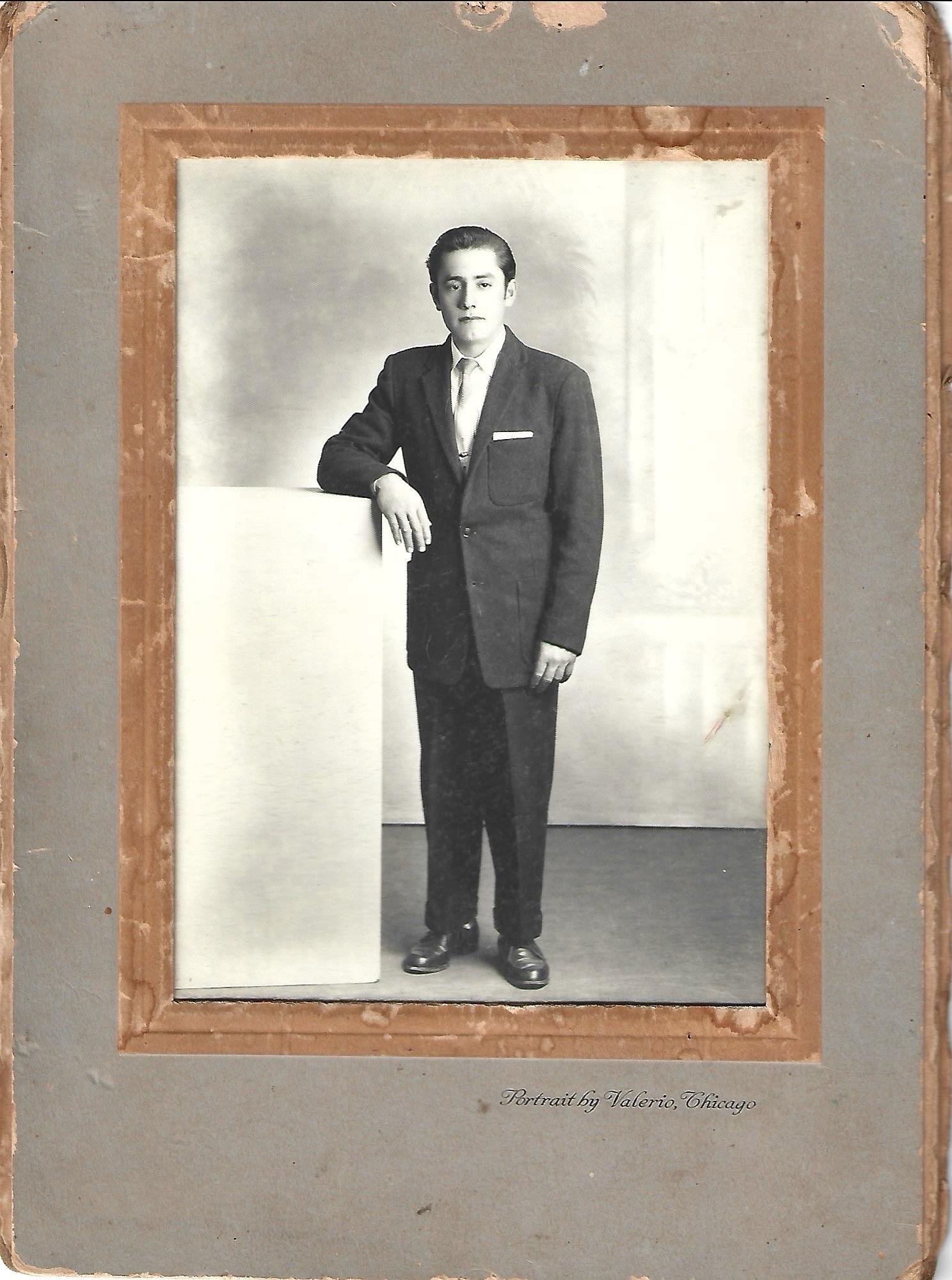 A man in a suit leaning on a wall