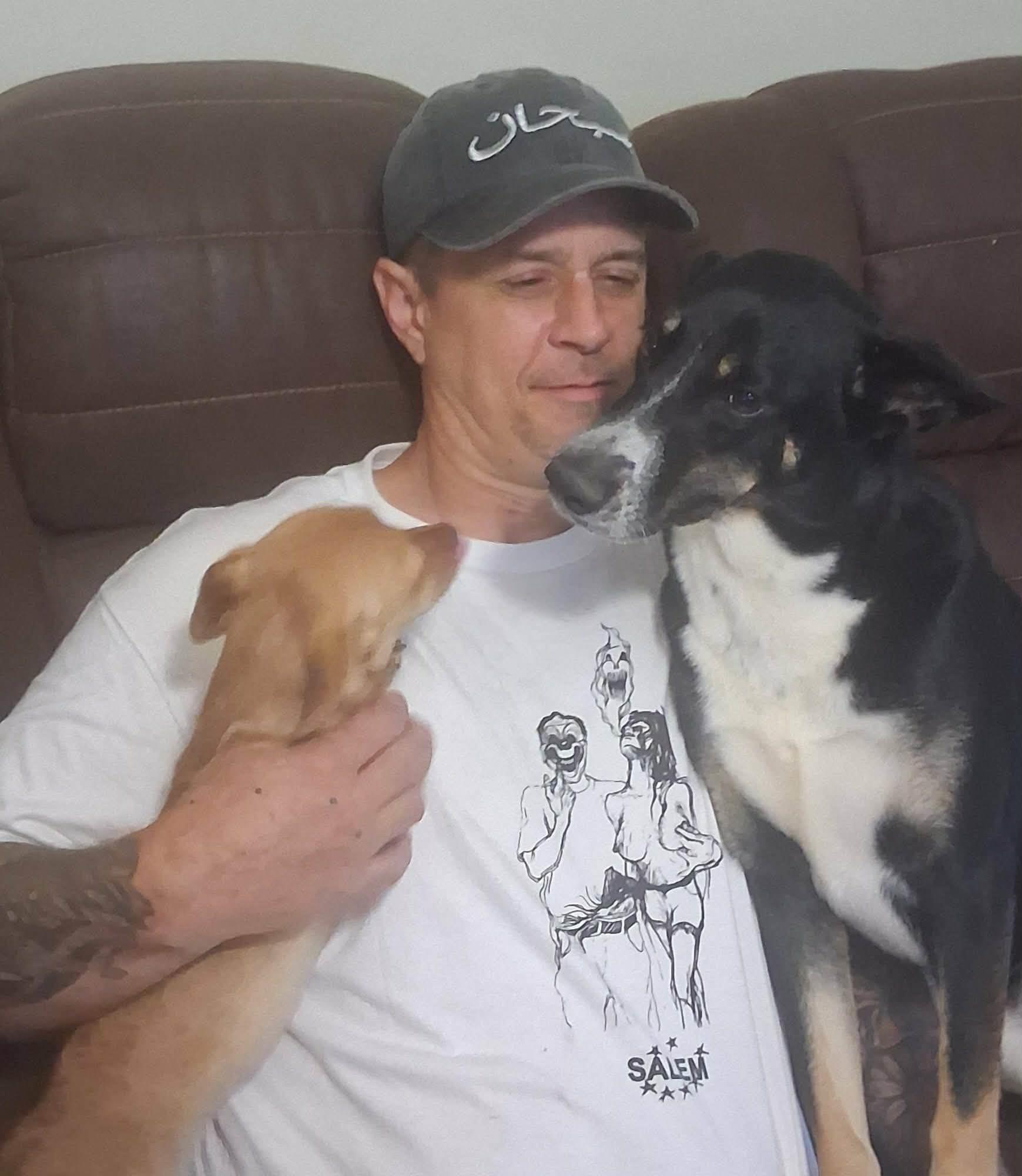 A man sitting on a couch with two dogs