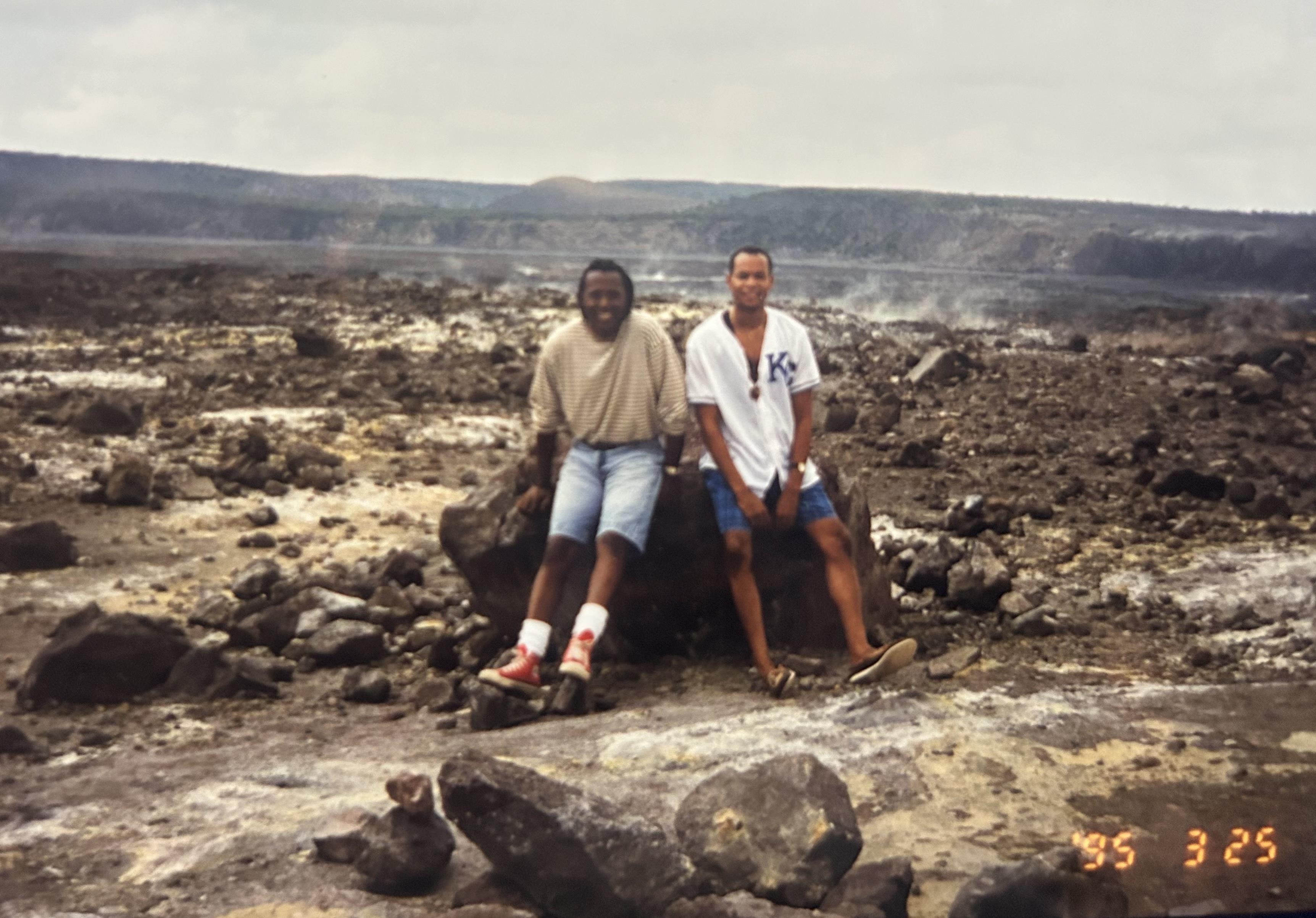 A couple of men sitting on a rock