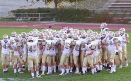 A group of football players huddle on a field