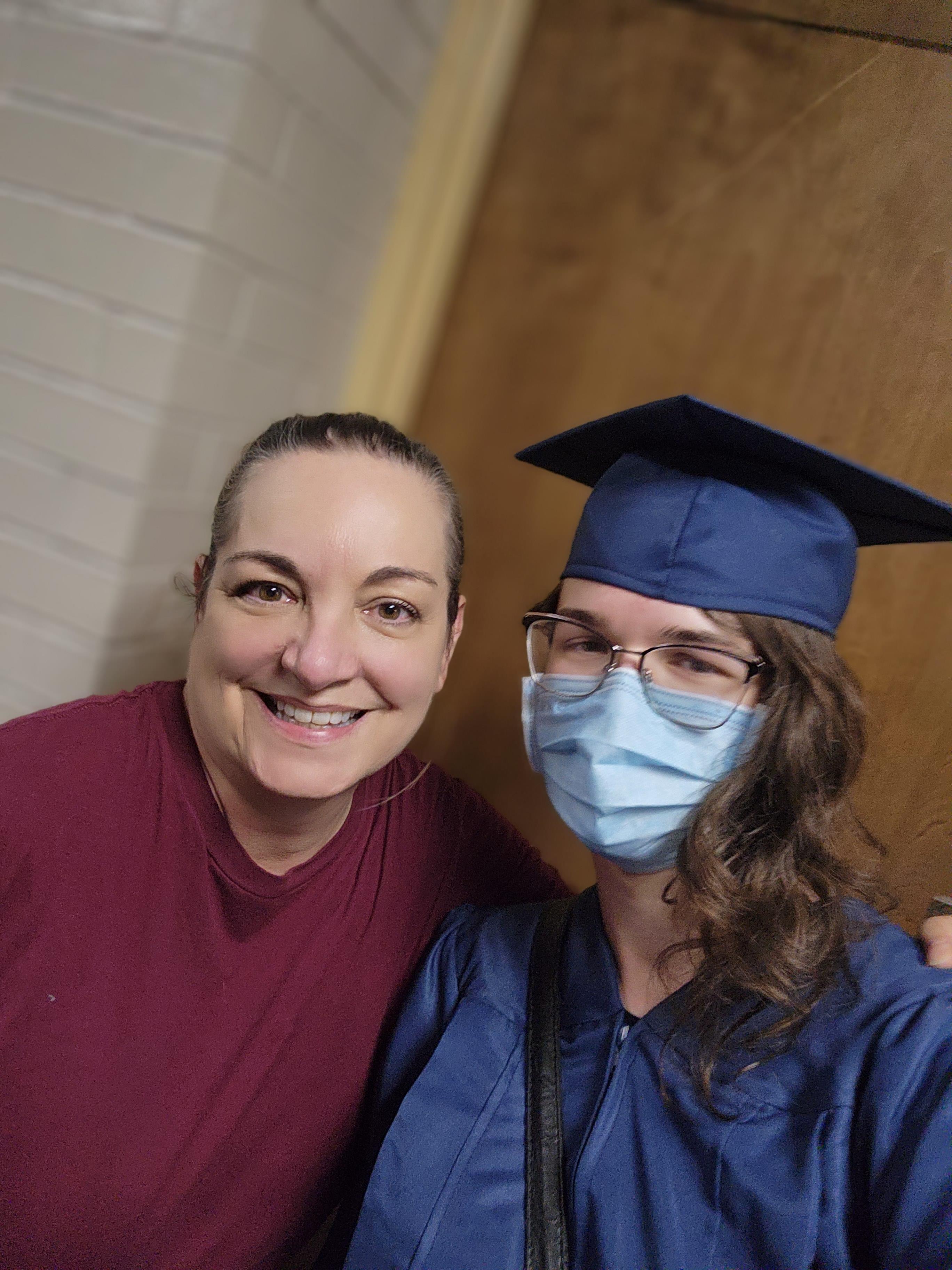 A woman wearing a cap and gown and a mask