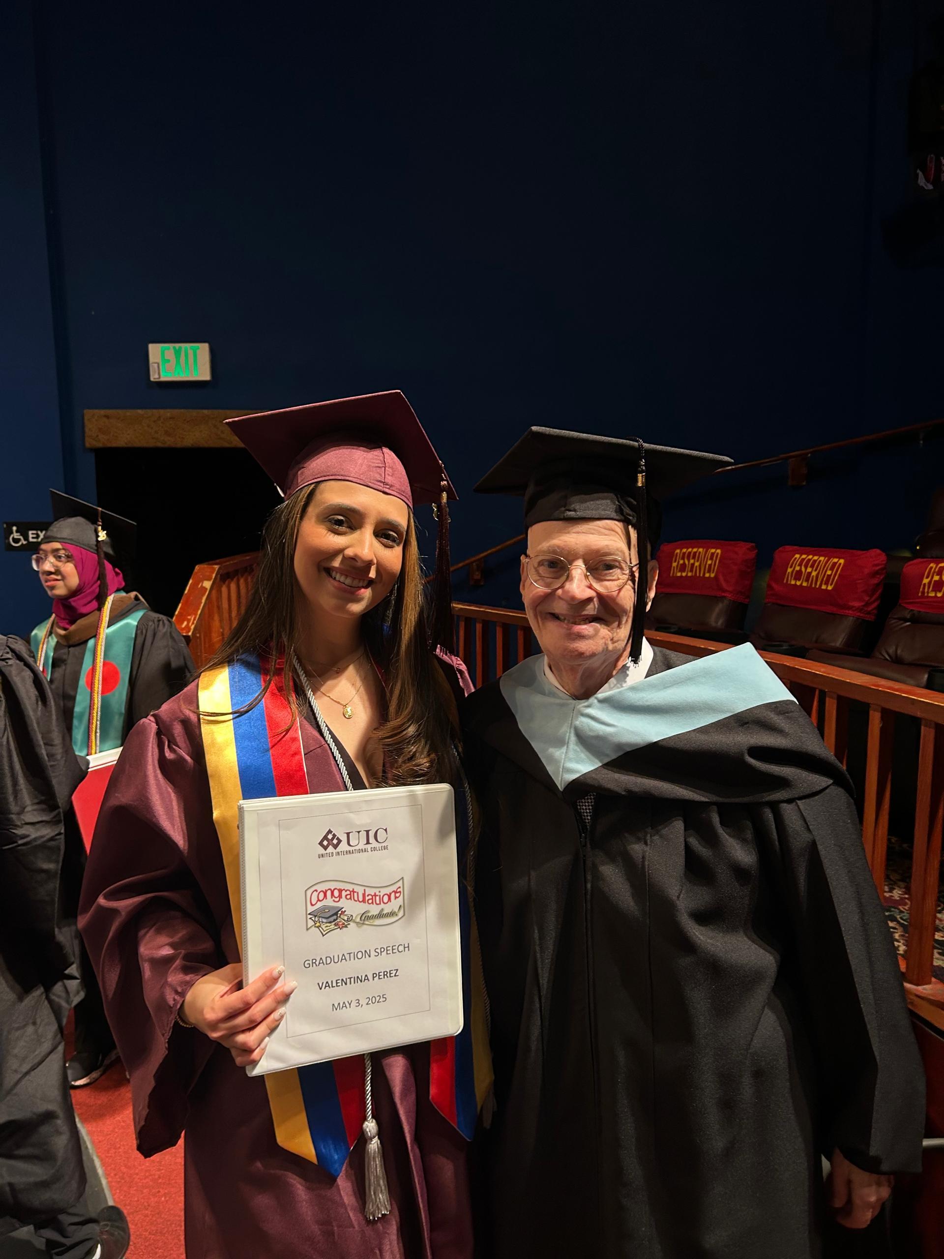 A woman in a graduation gown and cap holding a diploma