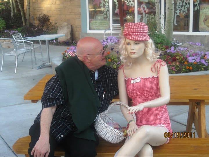 A man sitting on a bench with a mannequin
