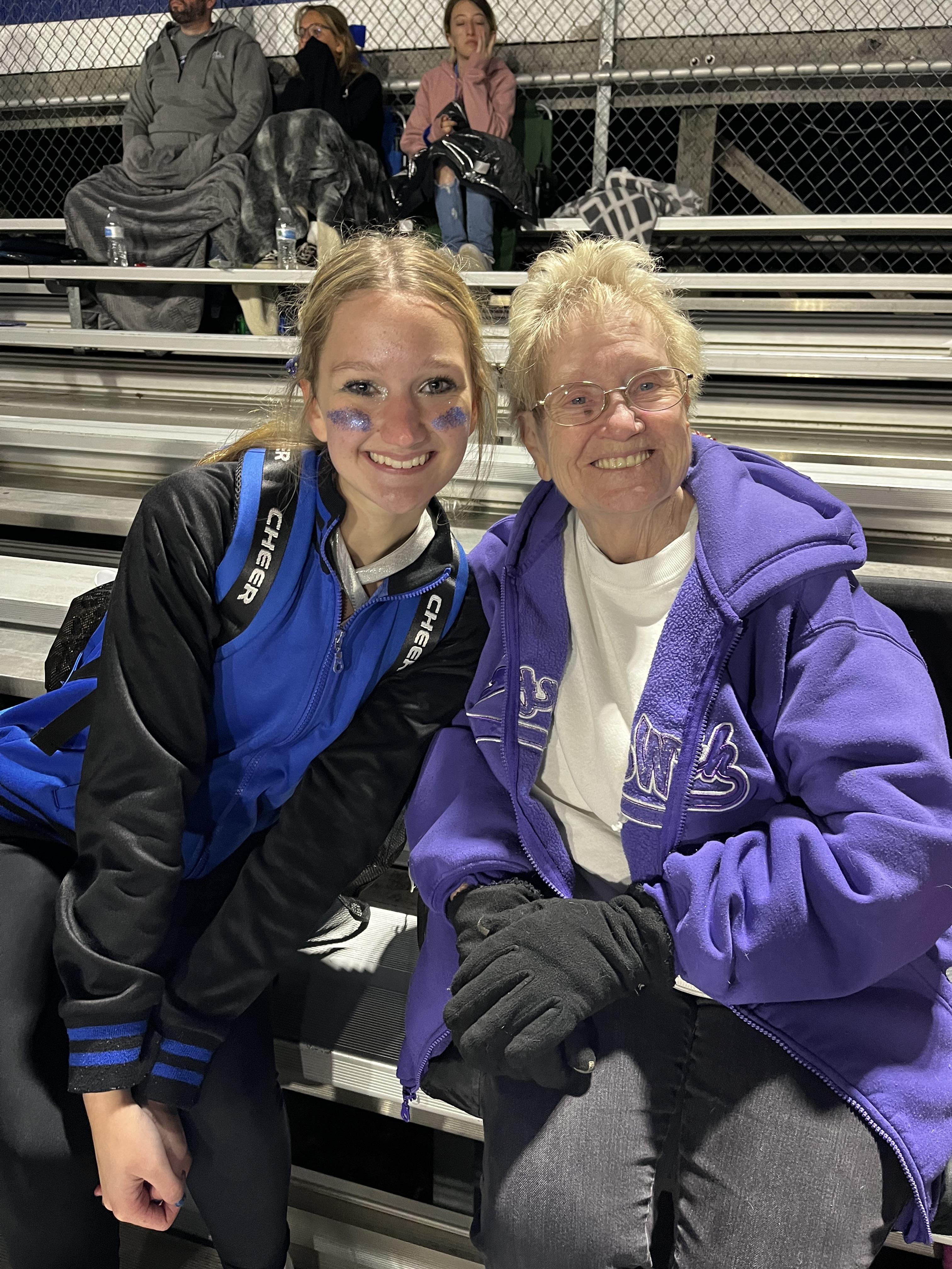 Two women sitting on bleachers smiling