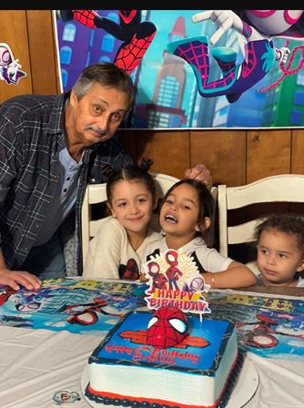 A man and two kids at a table with a cake