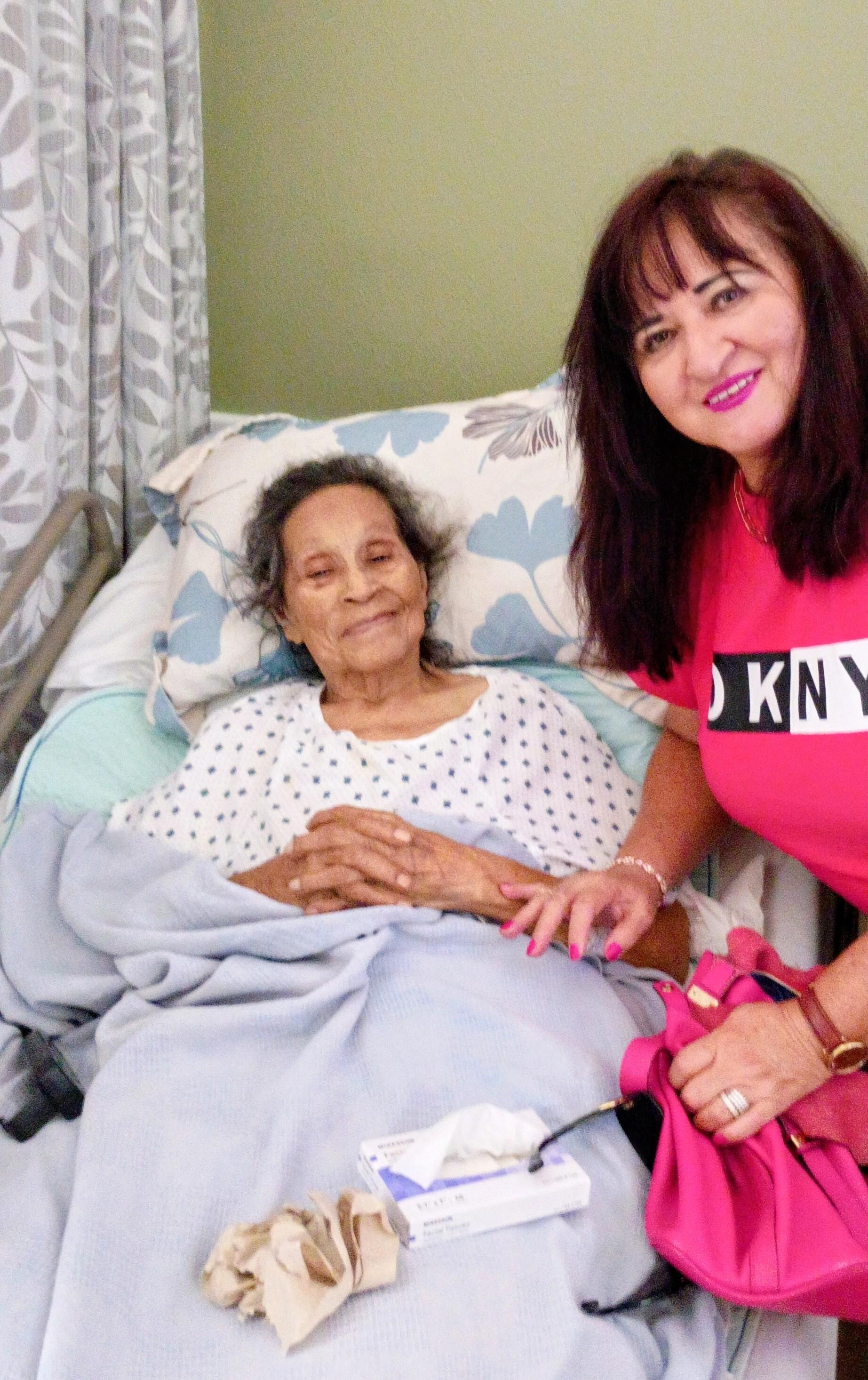 A woman in a hospital bed with a nurse