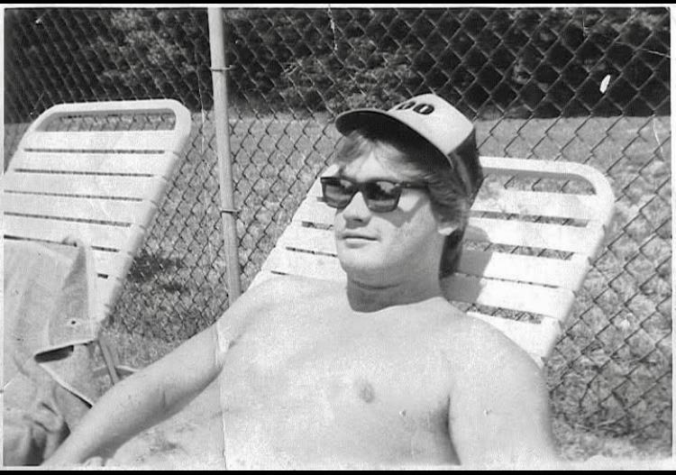 A man in a hat and sunglasses lying in a chair