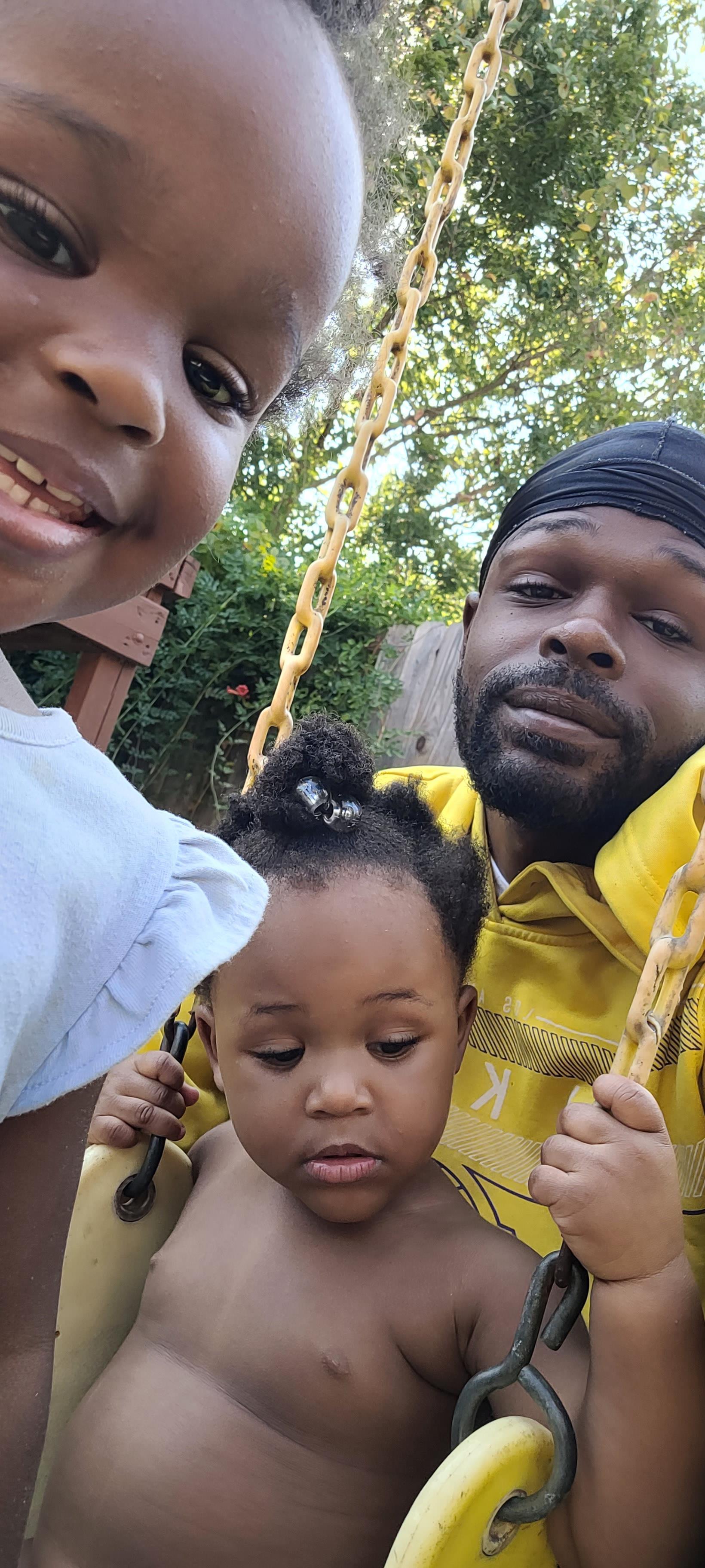 A man and two children on a swing