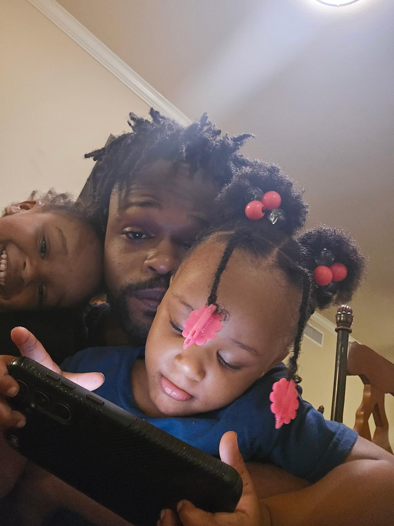 A man and two children looking at a cellphone