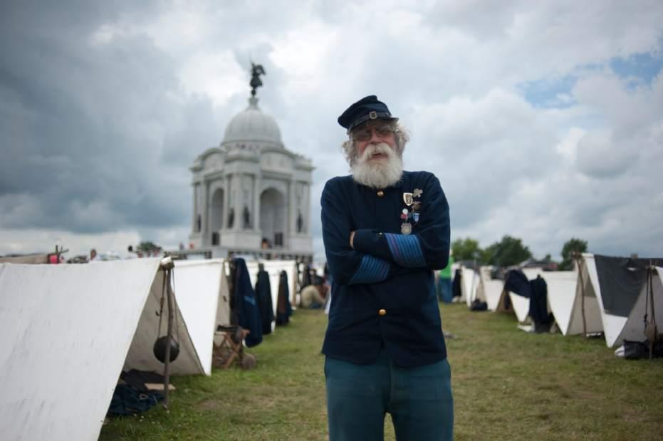 A man in uniform standing in front of tents