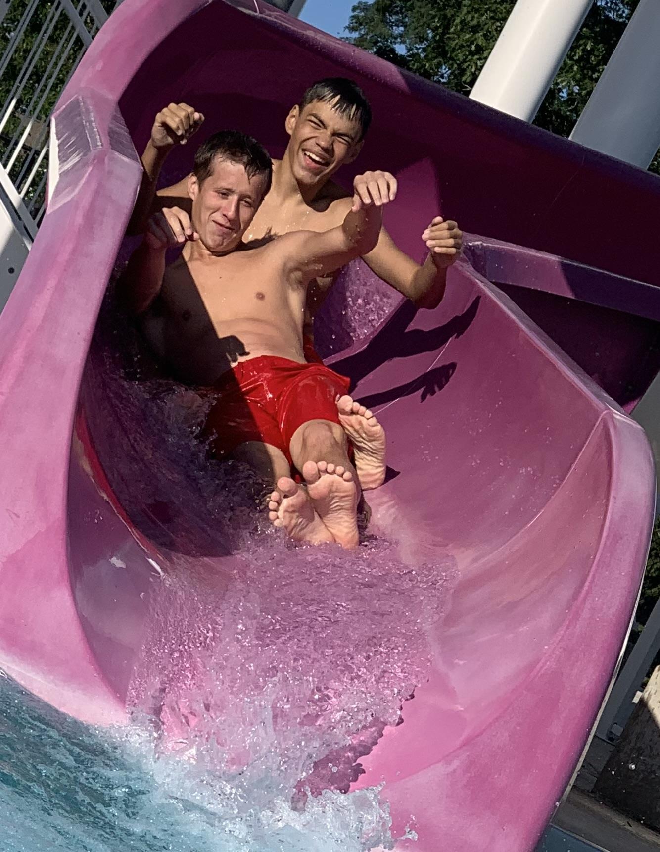 Two men sliding down a water slide