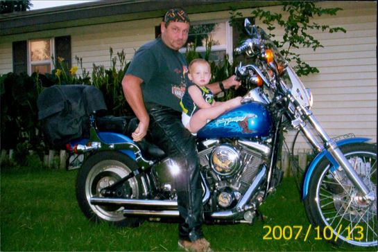 A man sitting on a motorcycle with a baby