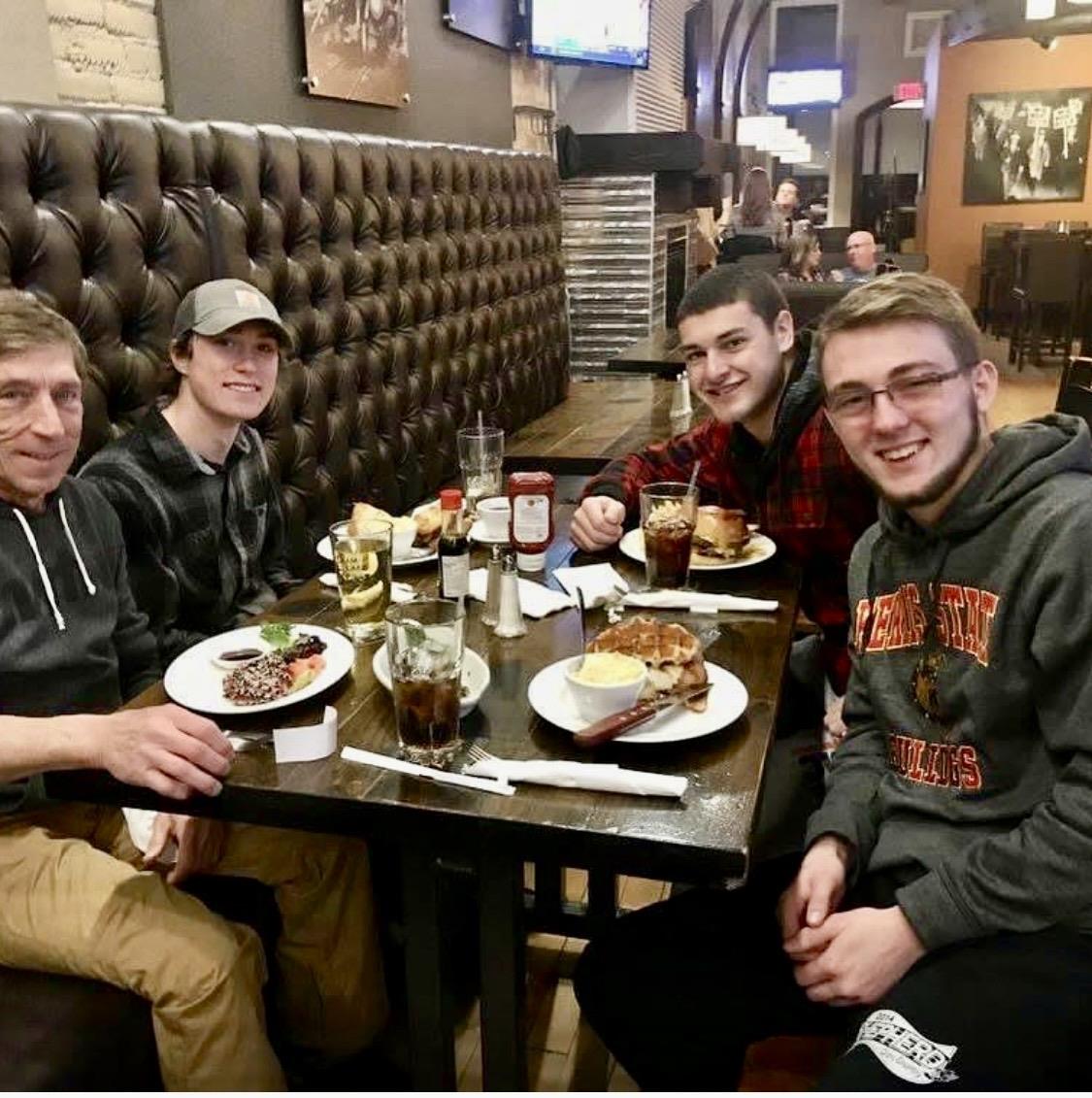 A group of men sitting at a table with food