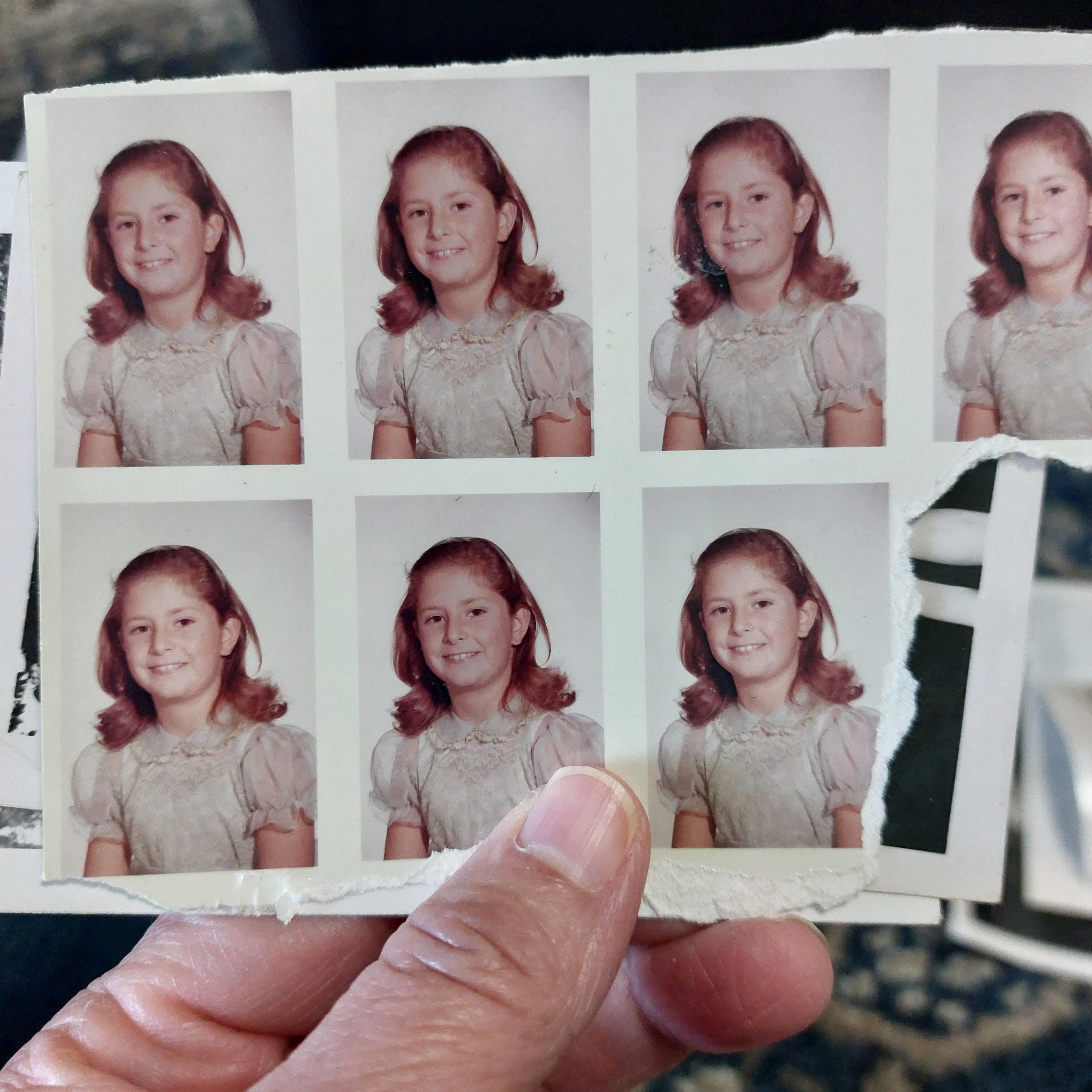 A hand holding a photo of a girl