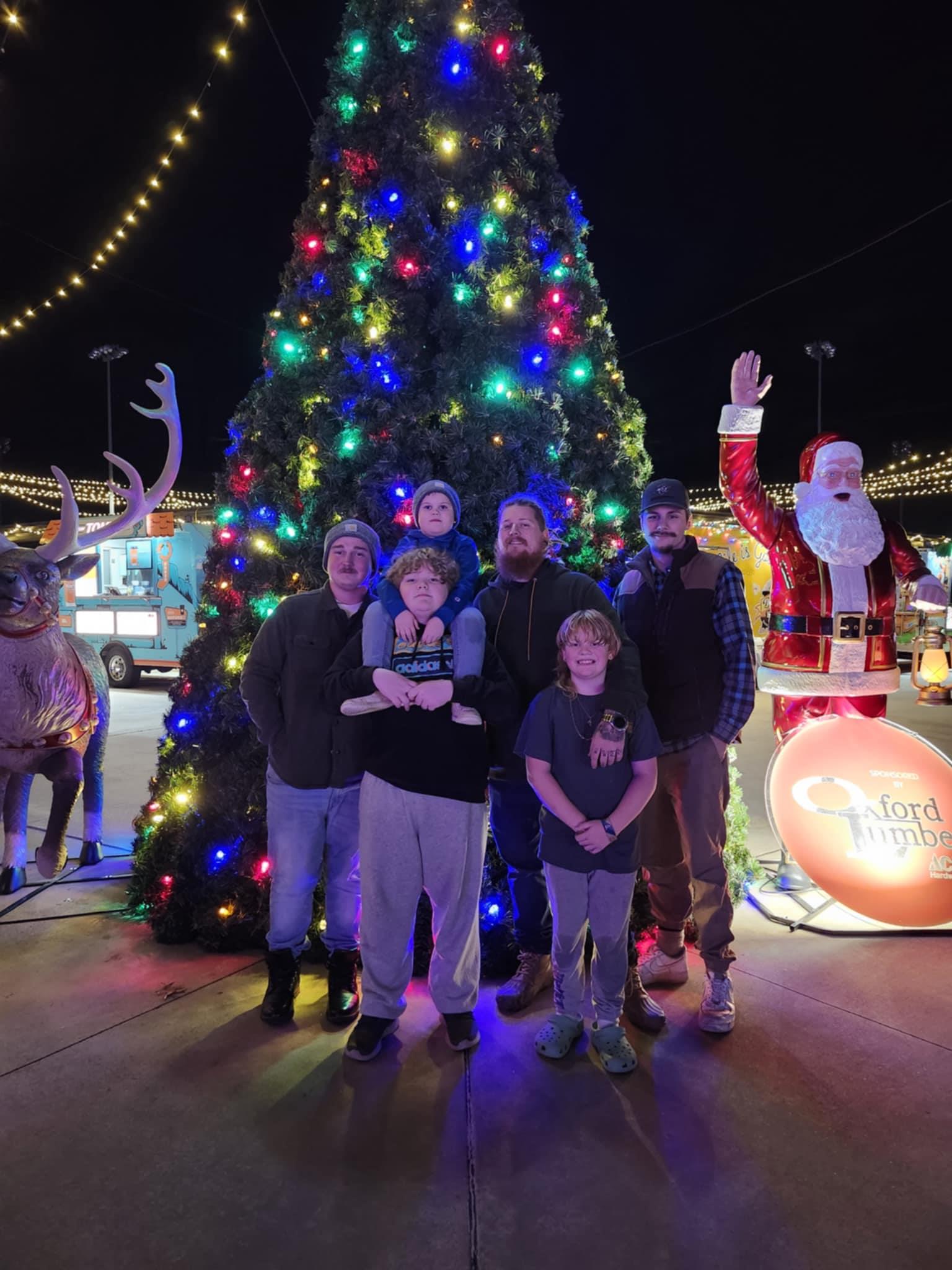A group of people posing in front of a christmas tree