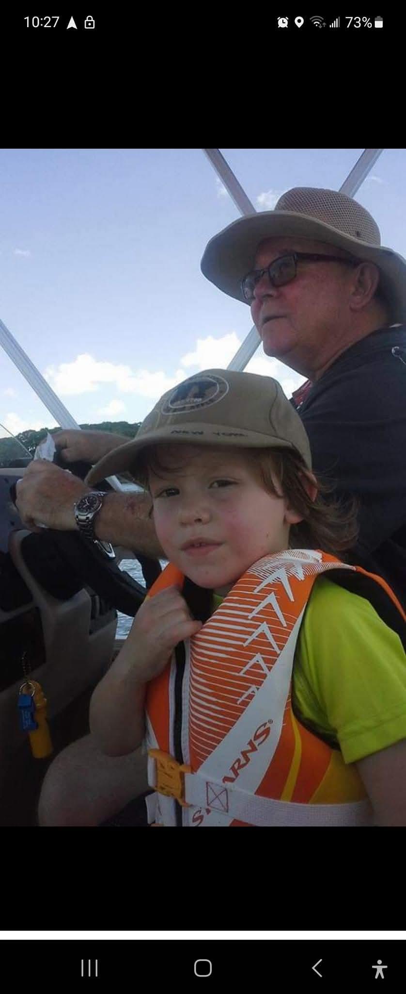 A boy wearing a life jacket and hat