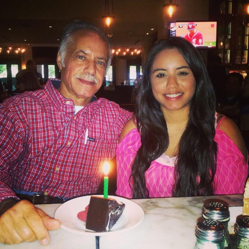 A man and woman sitting at a table with a cake and a lit candle
